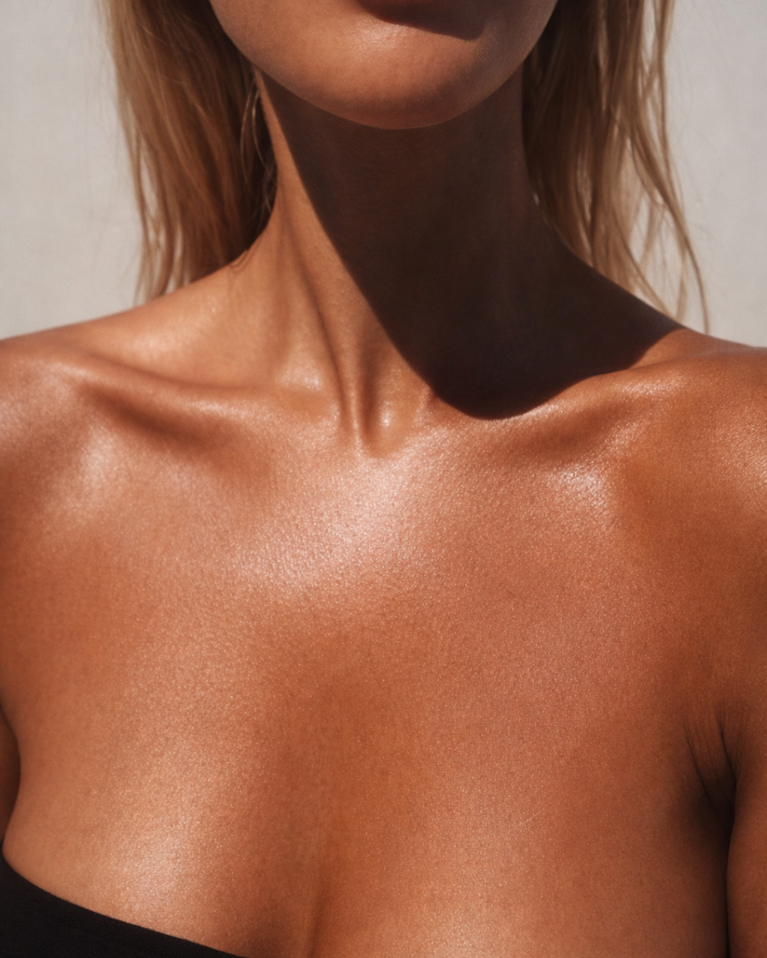 Close-up of glowing, bronzed skin across the collarbones and shoulders