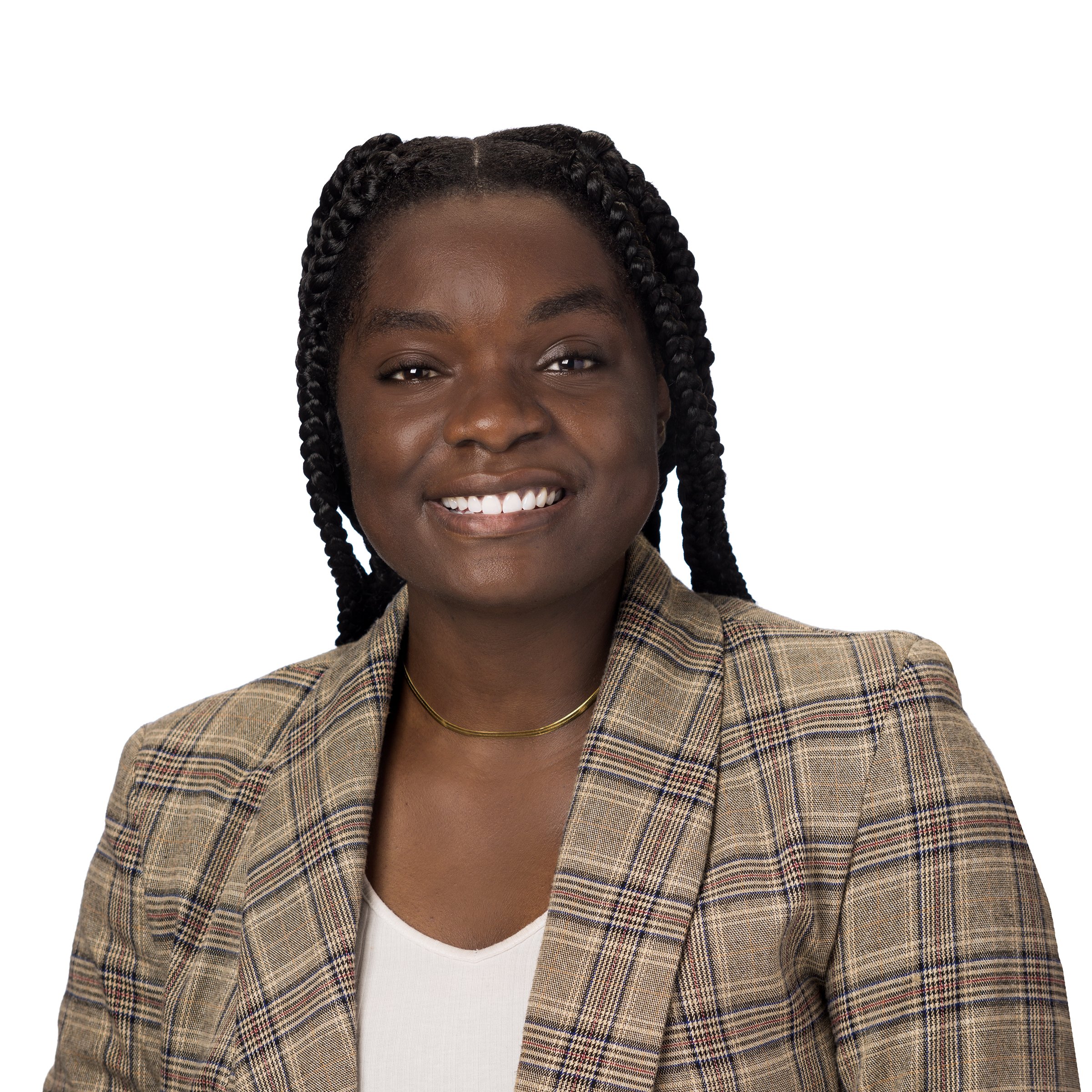 Person with short blonde hair smiling in a floral dress, standing in front of a leafy background.