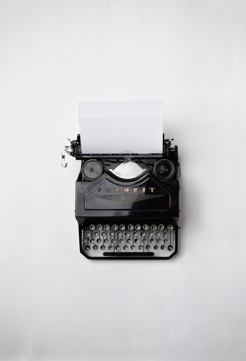 image of aerial view of black typewriter sitting on white desk