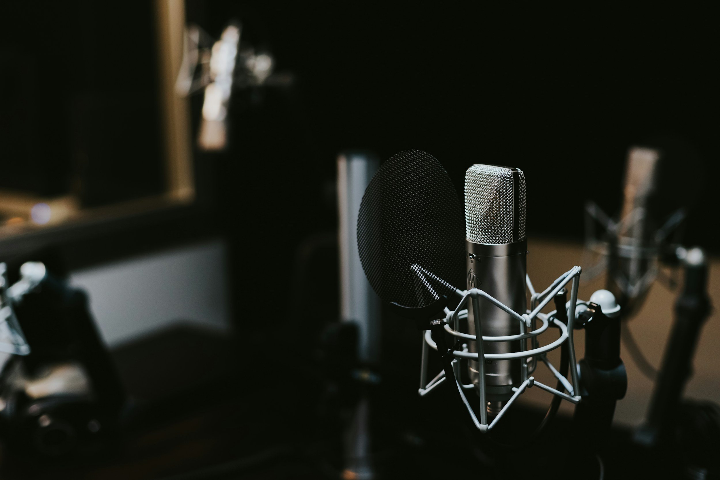 Close-up of a professional microphone with a pop filter in a recording studio, dark background