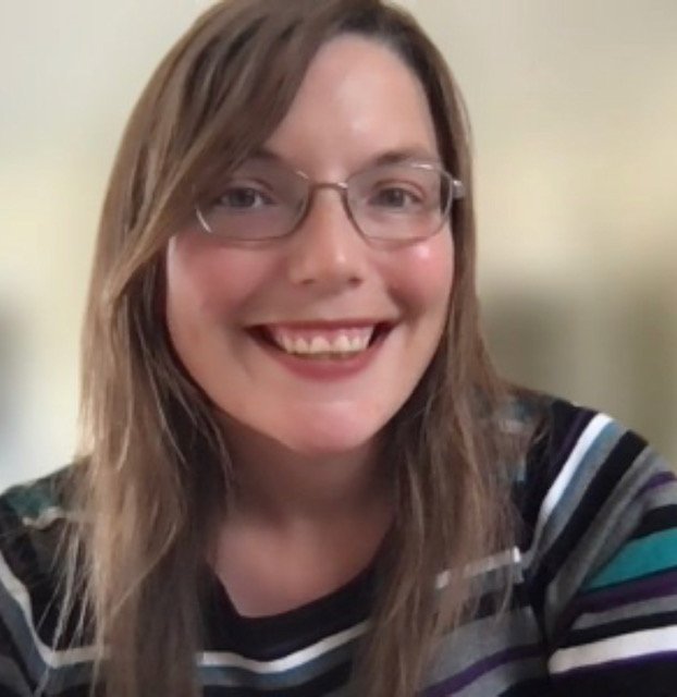 A woman with light brown, shoulder-length hair and glasses smiling at the camera.