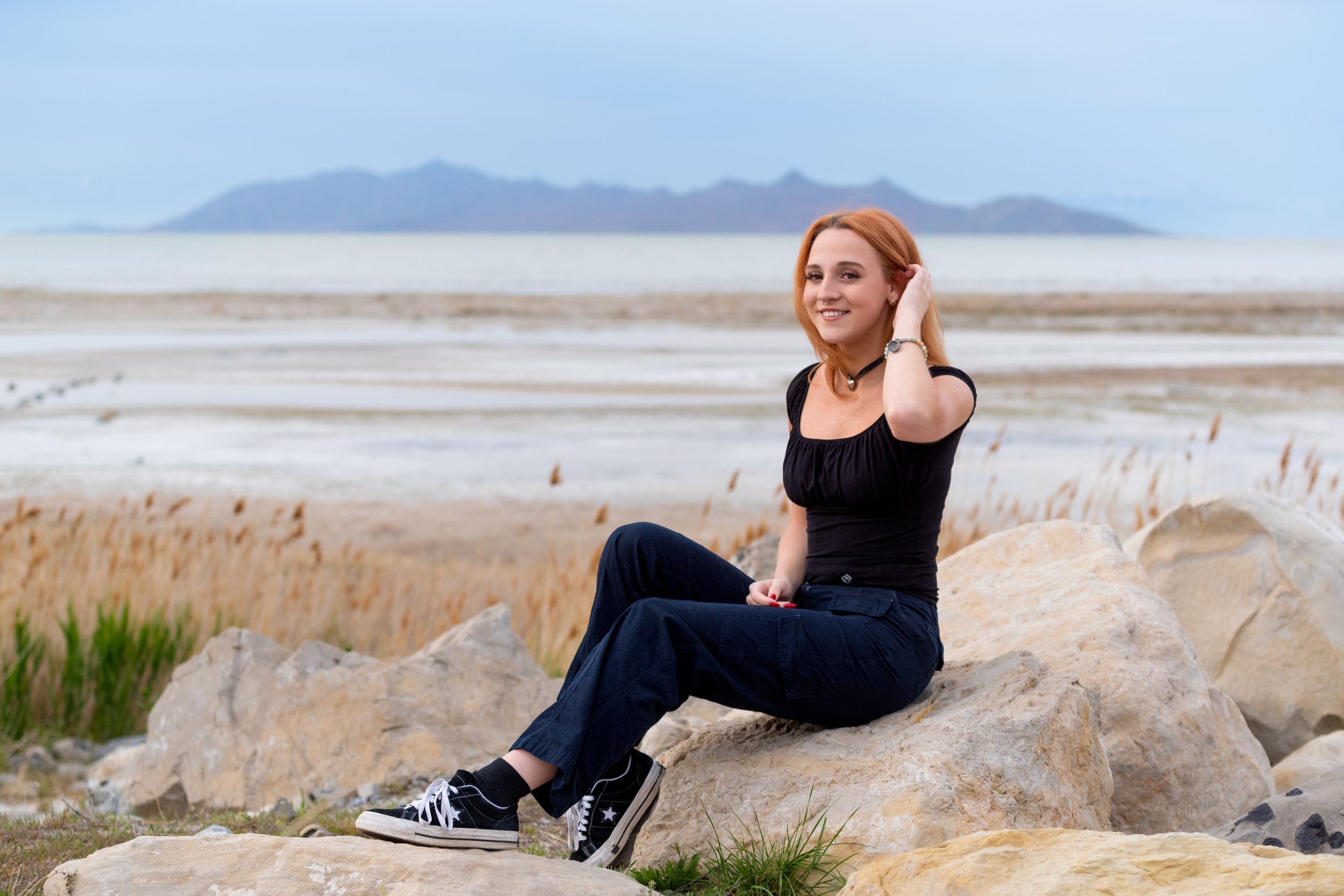 A high school senior girl sitting on rocks at evening near the Great Salt Lake