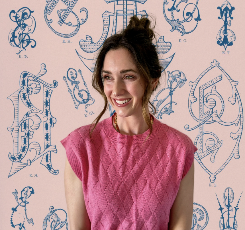 A young woman with brown hair styled in a half-up bun, wearing a pink knitted sleeveless top, smiling and looking to her right, Luxury fashion and marketing, CEO, Taylor Allen