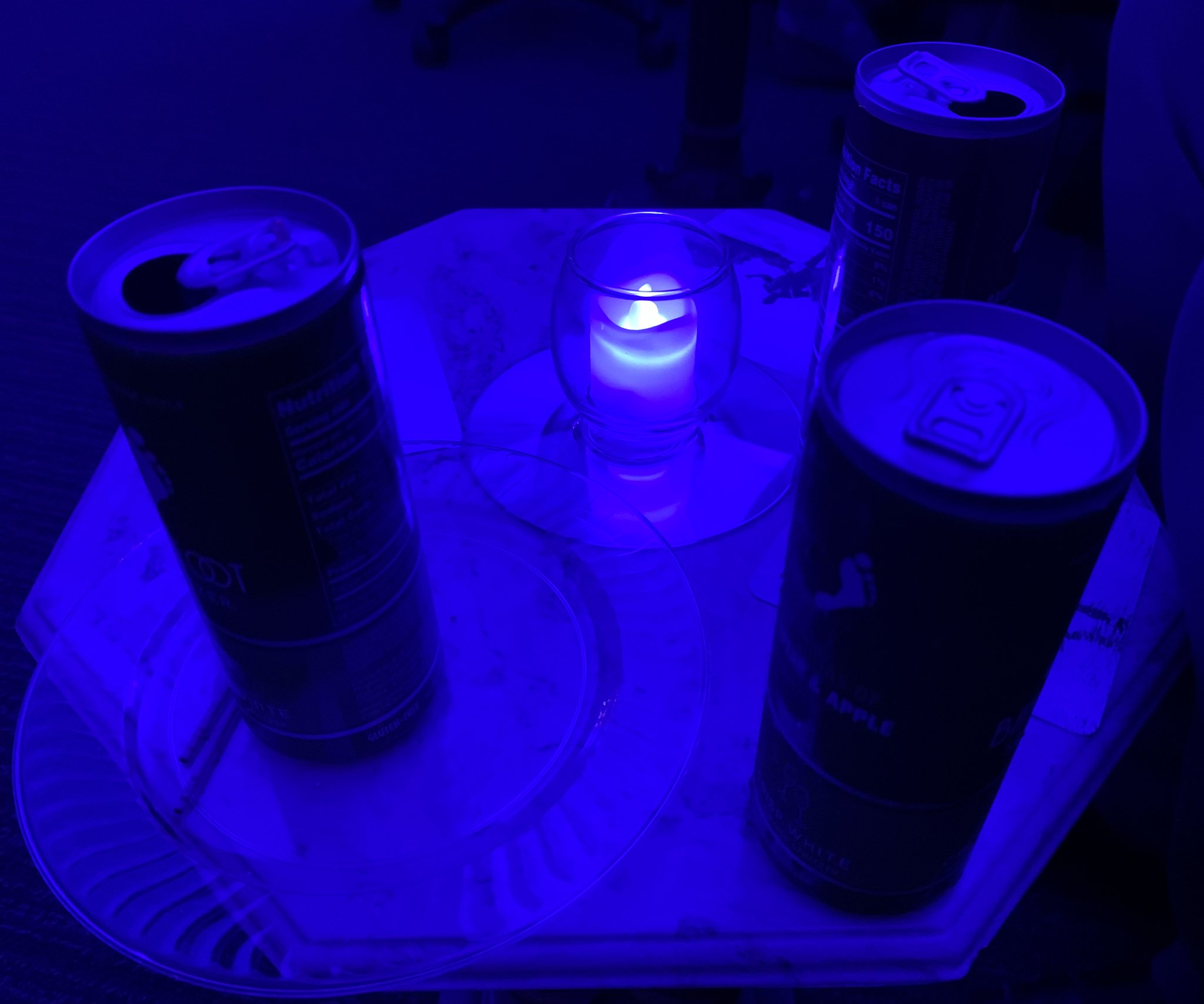 three beverage cans and blue tealight candle