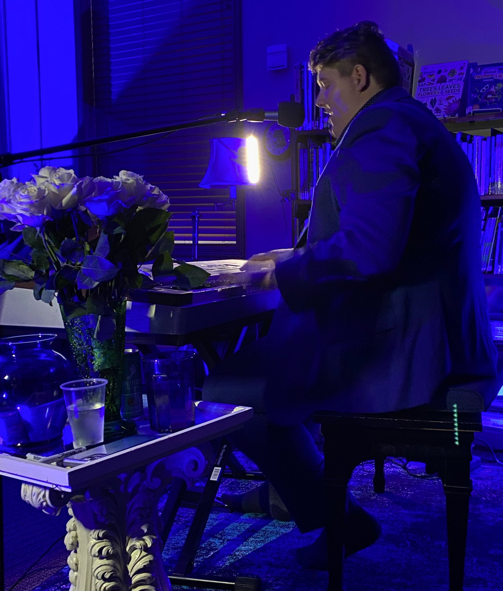 bouquet of white roses sits next to Alex while he performs