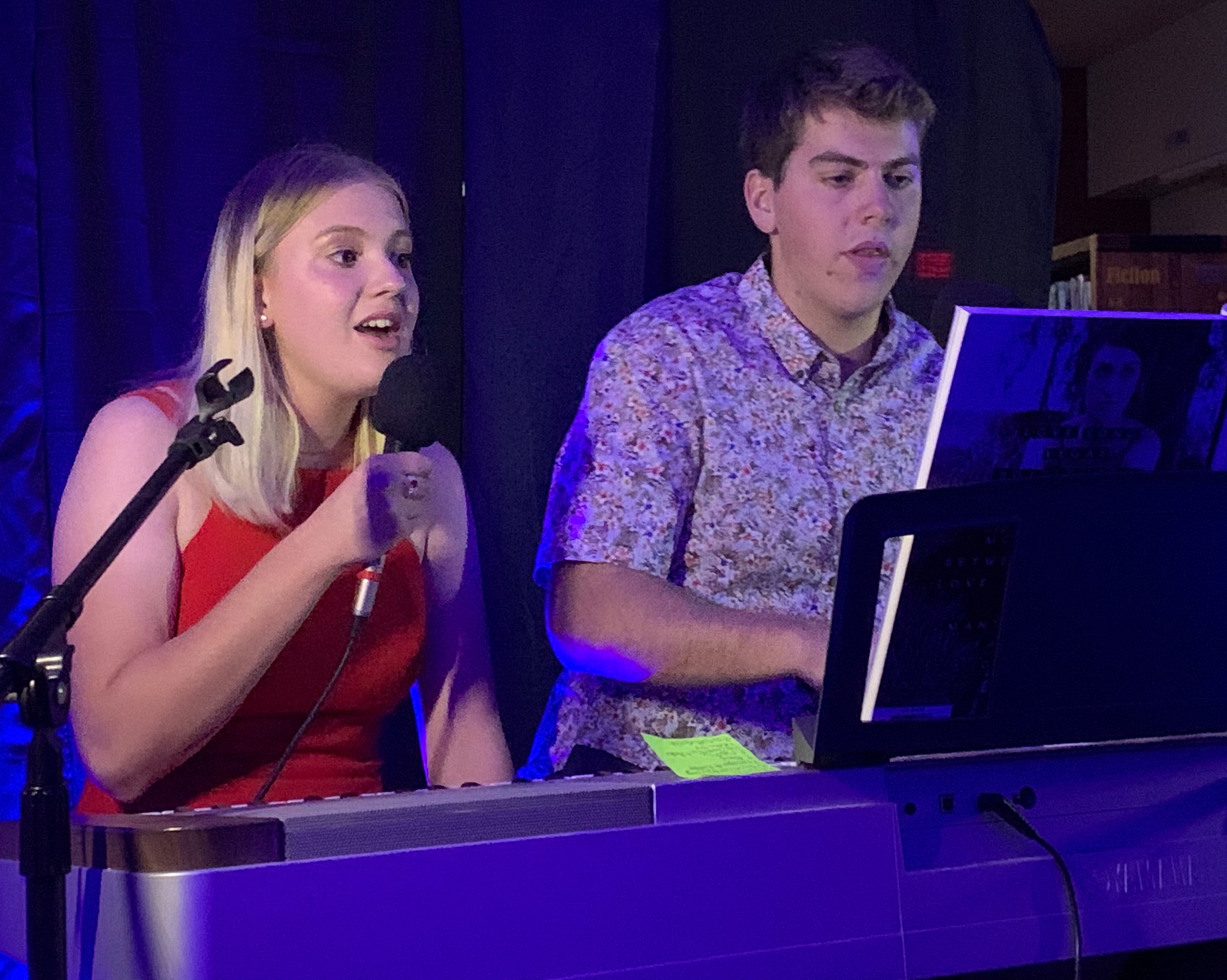 two people perform at the piano