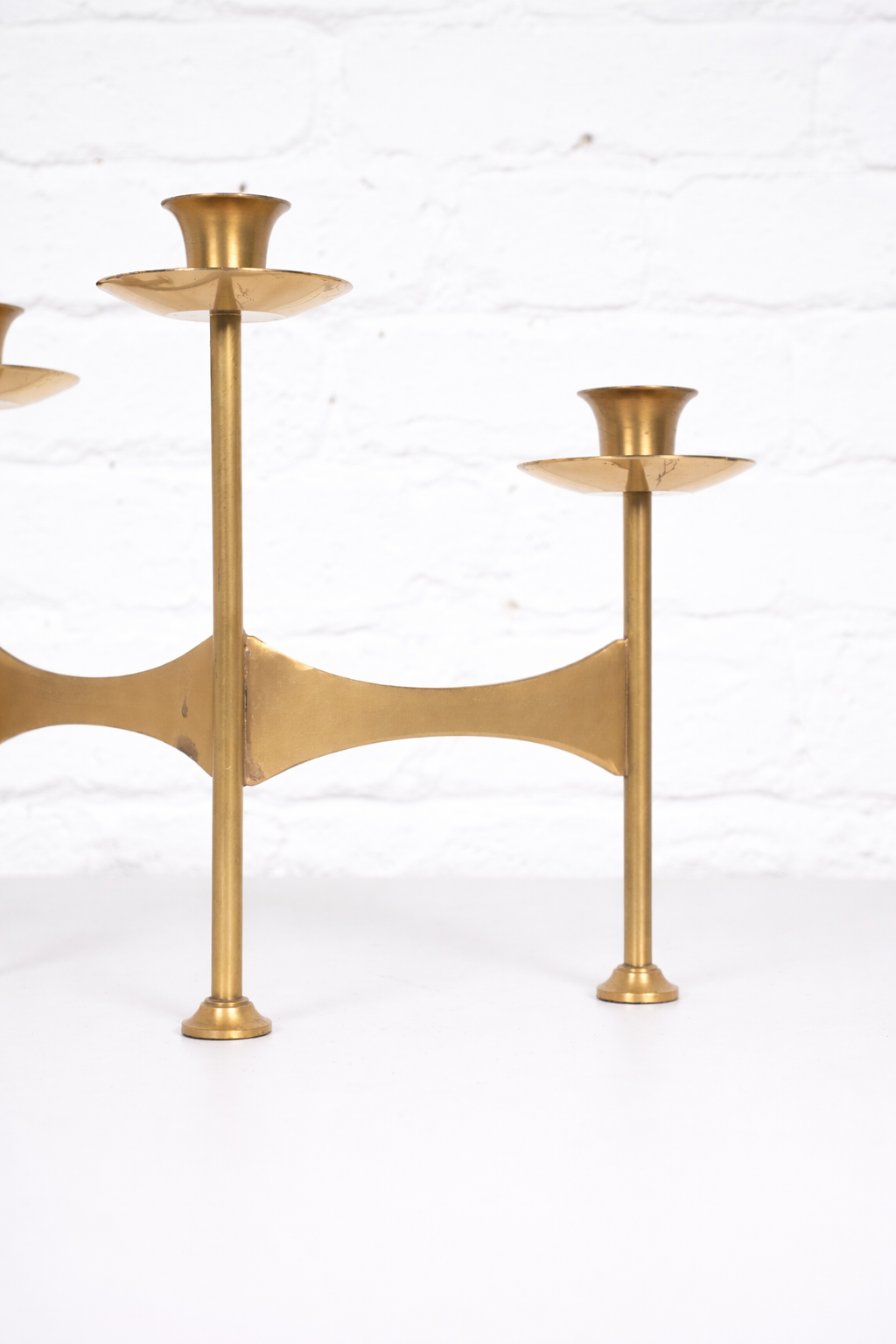 Elegant brass candelabra against white wall.png