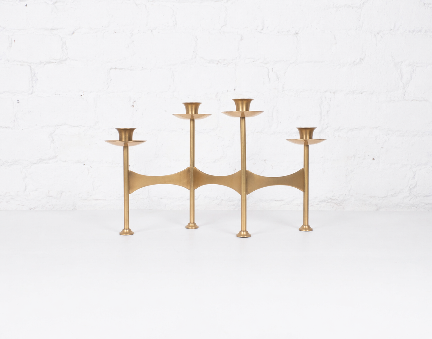 Minimalist brass candelabrum on white surface.png