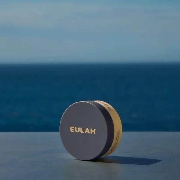 An image of the Eulah Cleansing Balm with the sea in the background