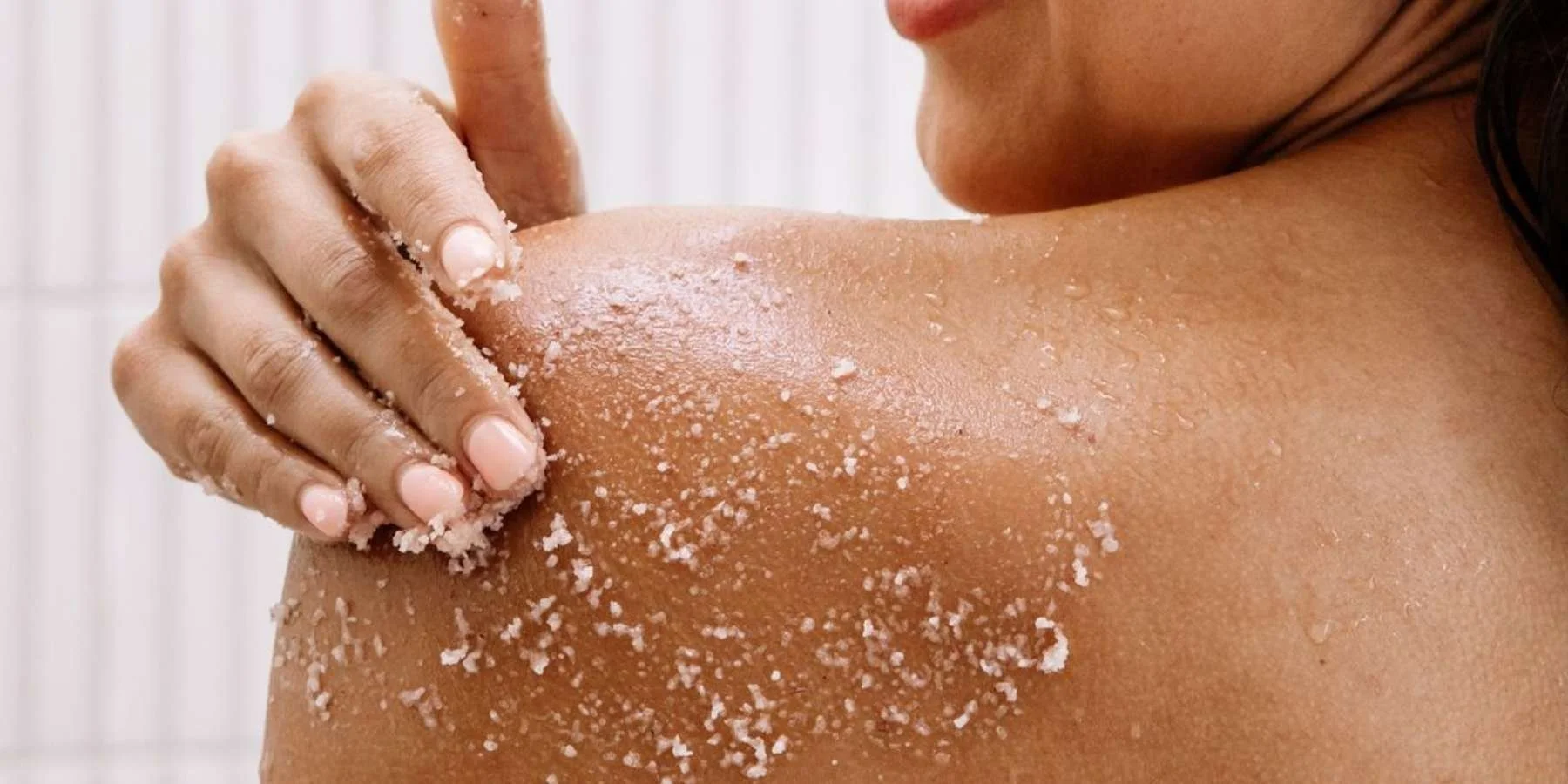 Woman's hand rubbing exfoliator onto shoulder