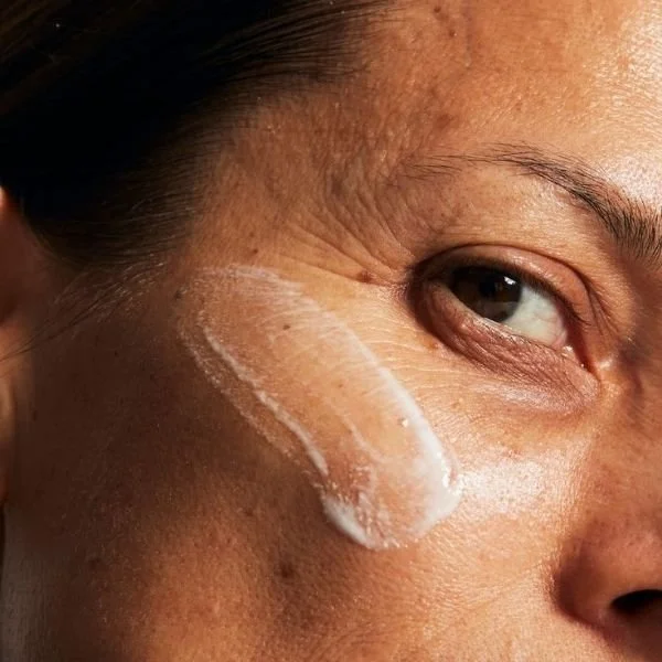 A close up of a woman's cheekbone with a swatch of cream applied