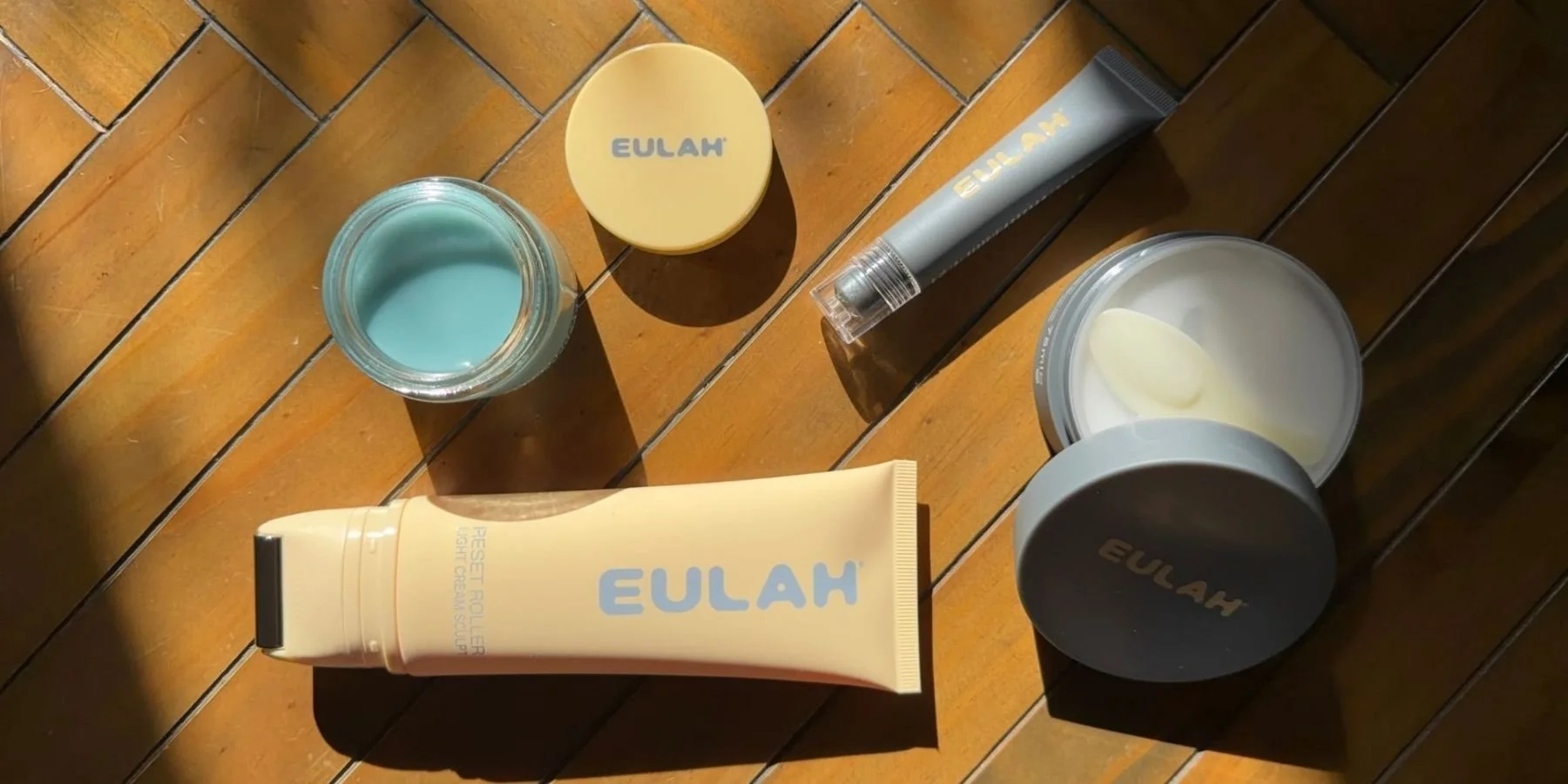 A range of Eulah skincare products laid along a wooden floor with a stream of sunlight pouring in