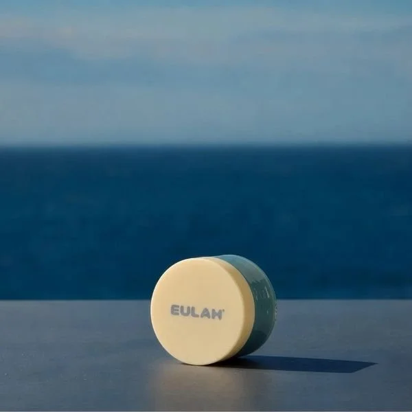 A round facial product in front of the ocean