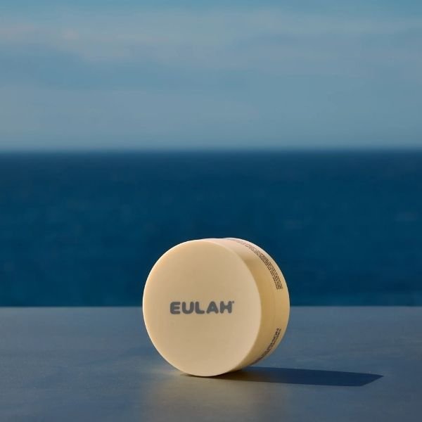 A round box of Eulah eye patches in front of the sea