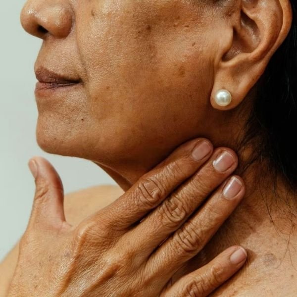 A close up of a woman touching her neck and jawline