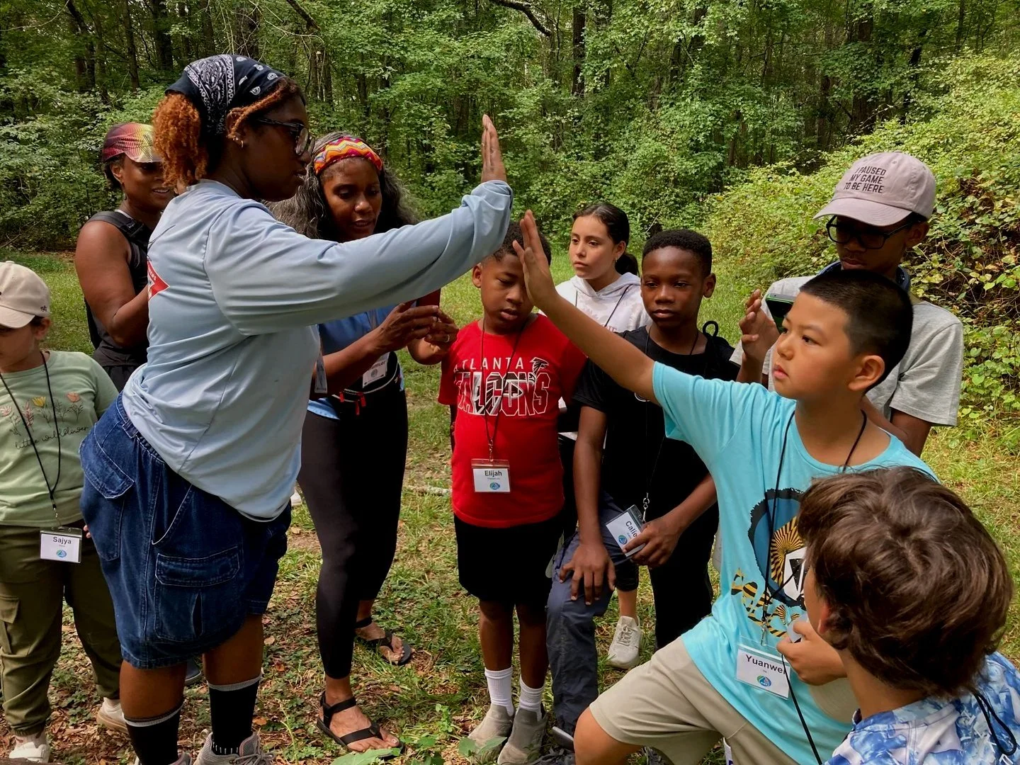 Group of children hiking and one child giving a high five to the instructor.