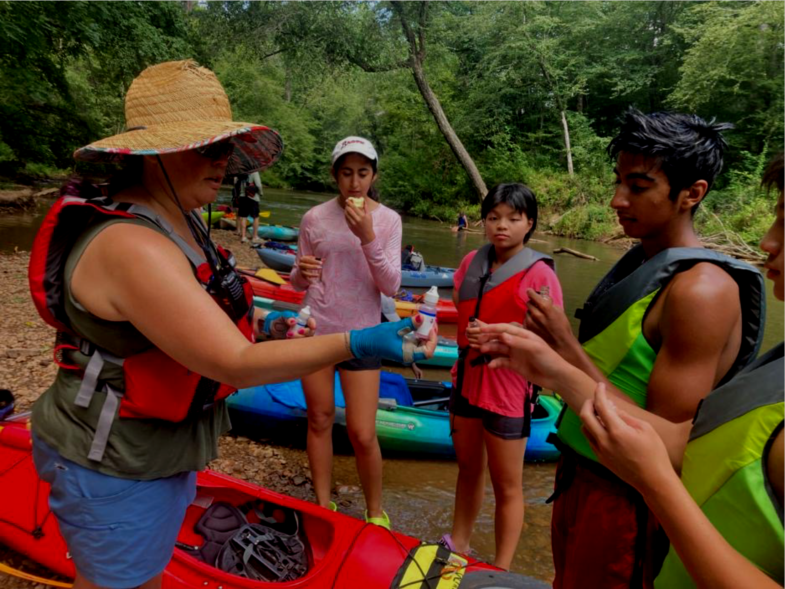 Woman instructing children about water testing on a river