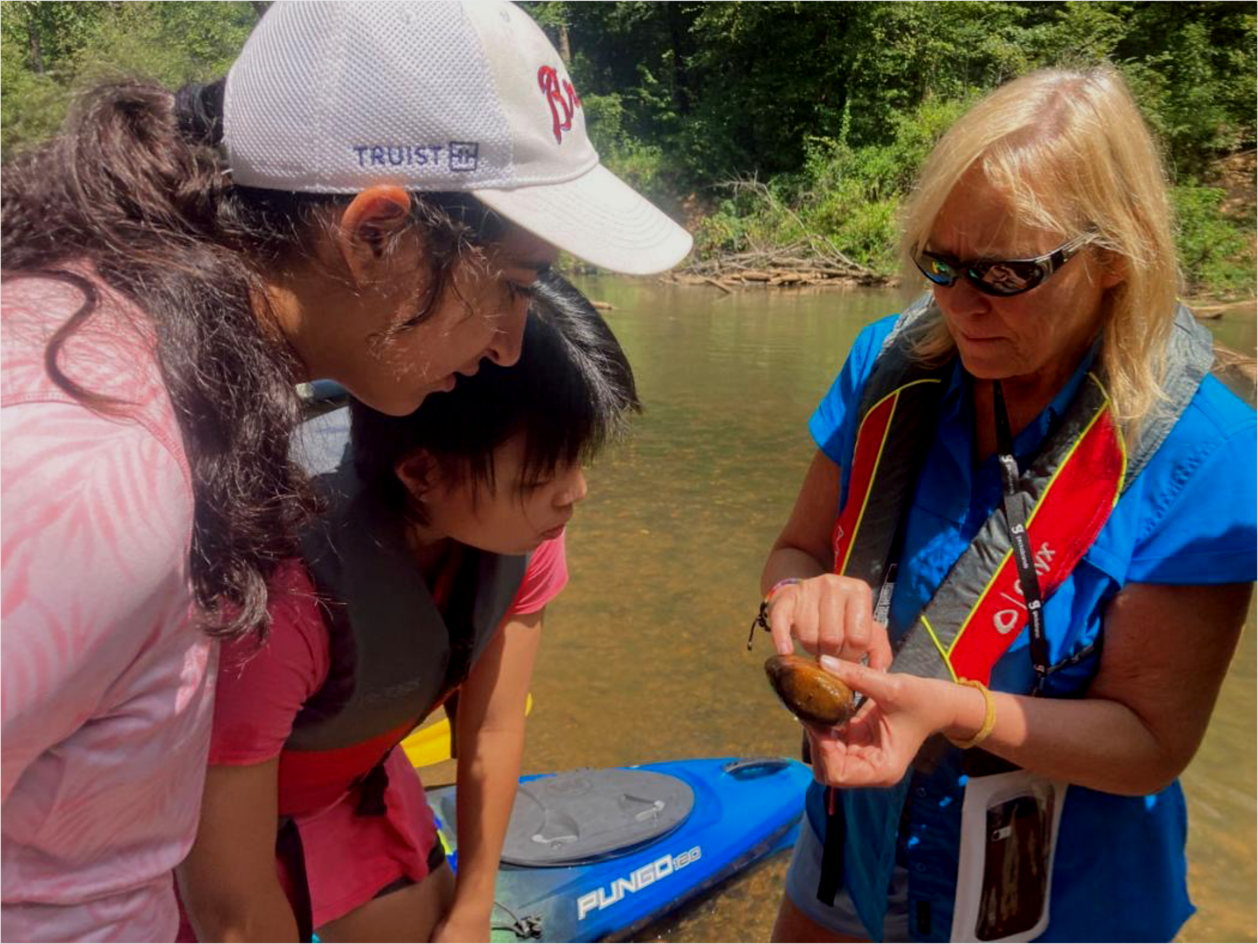 A woman showing teenagers a rock from the river.