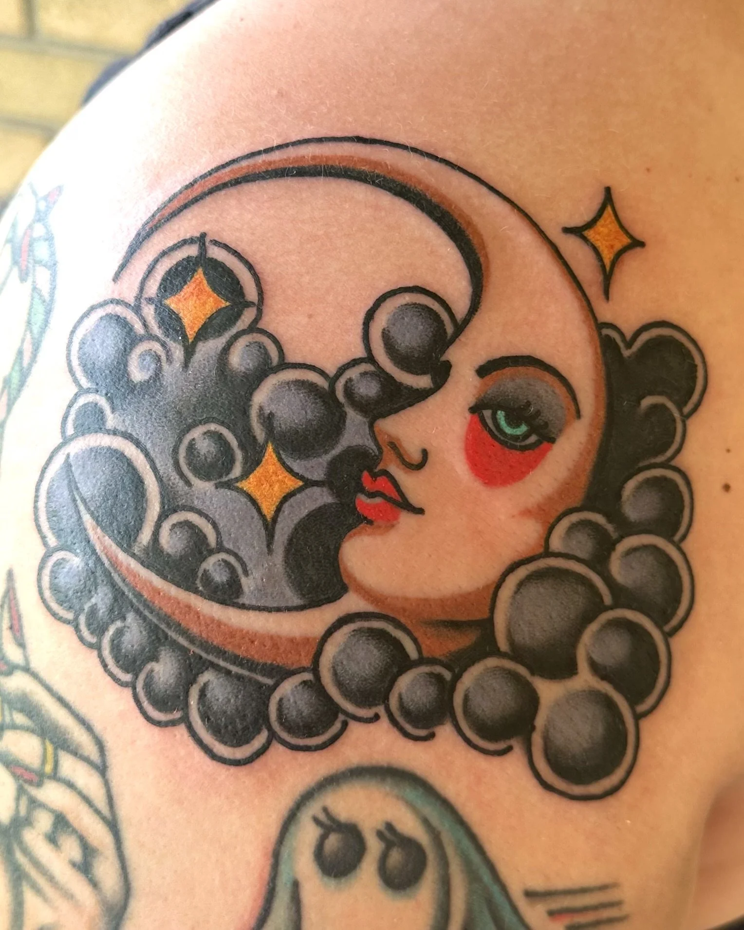 Tattoo of a woman's face with dark hair, green eyes, red lips, and lips with a starry background and circular design elements.