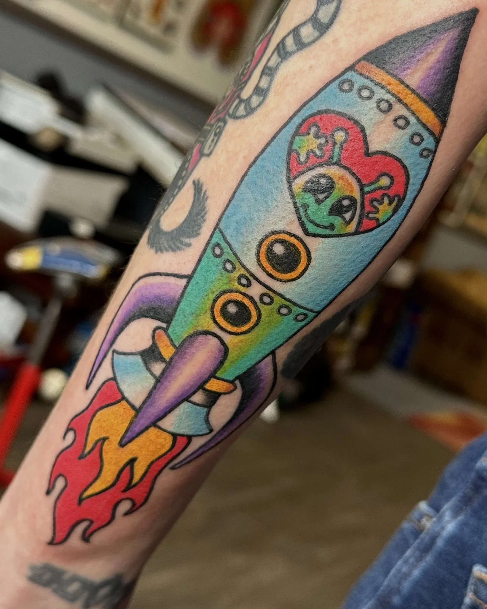 Colorful tattoo of a rainbow with clouds and stars on a person's arm.