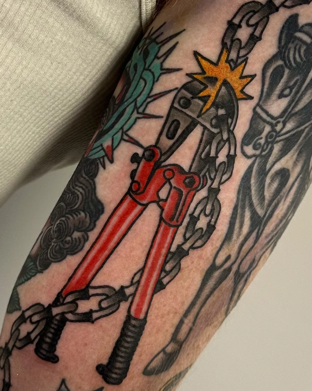A tattoo featuring a gun, chains, a star, and other decorative elements.