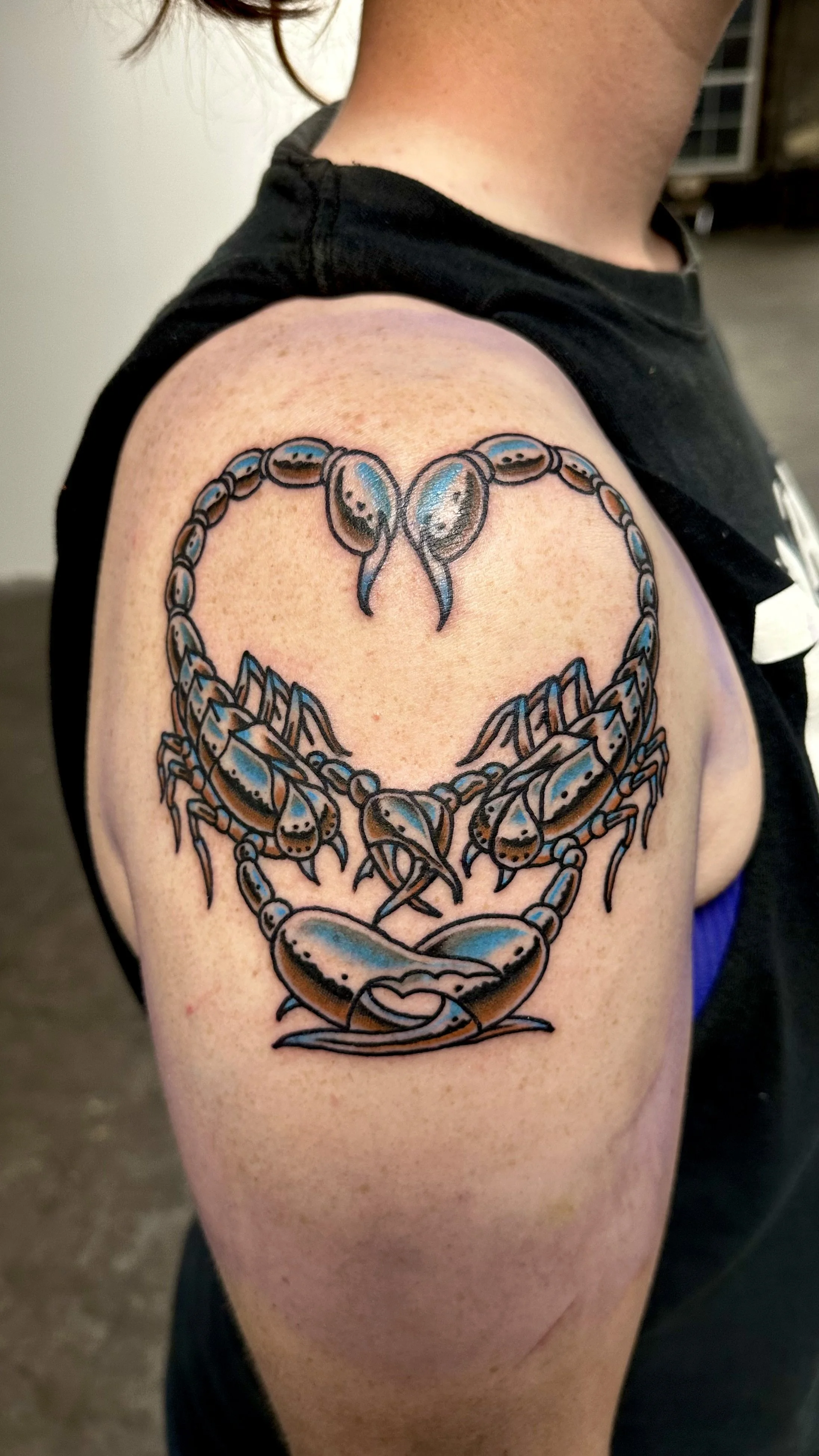 Tattoo of a heart-shaped crab outline on a person's upper arm.