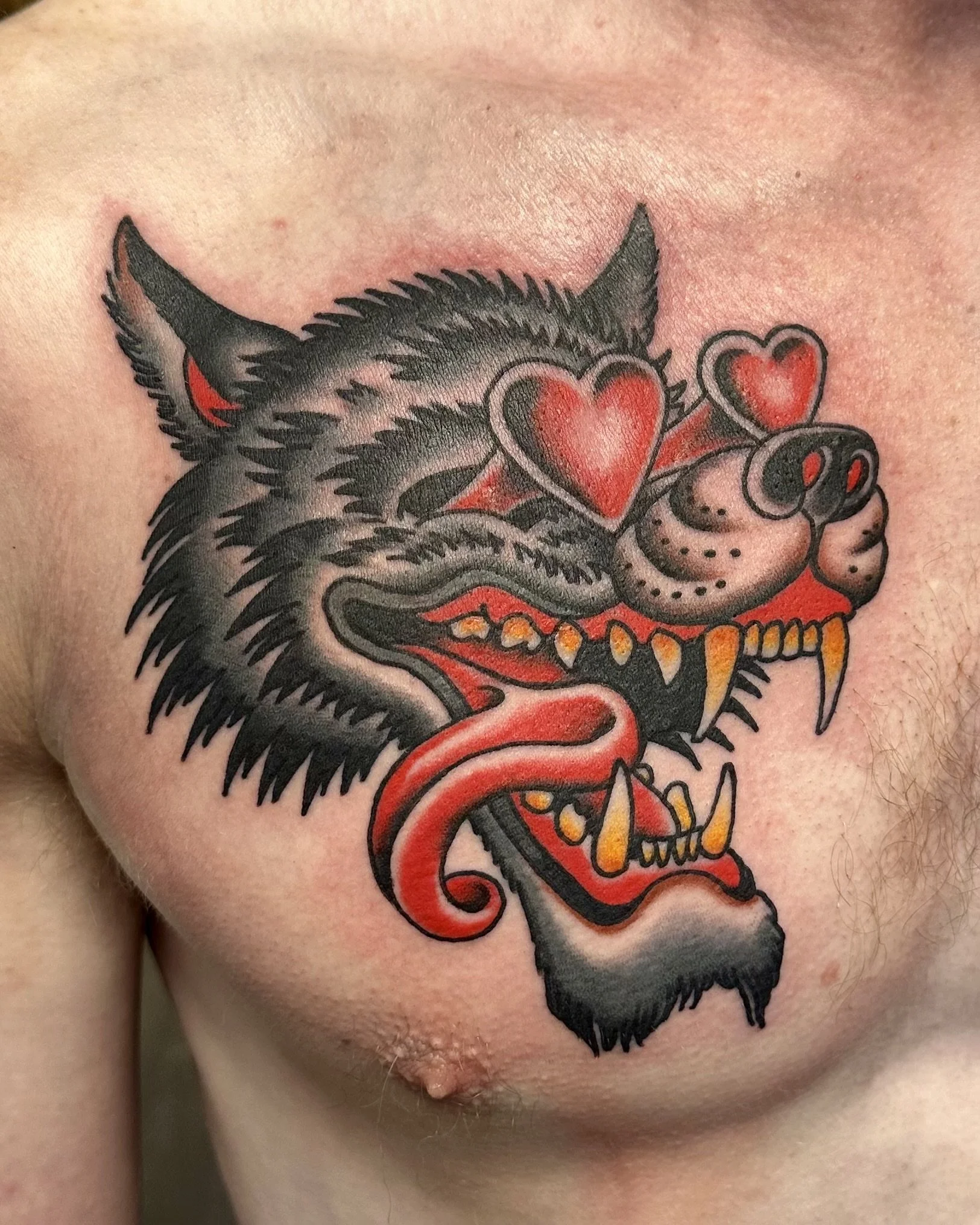 Colorful tattoo of a wolf with three red hearts on its face and a snarling expression.