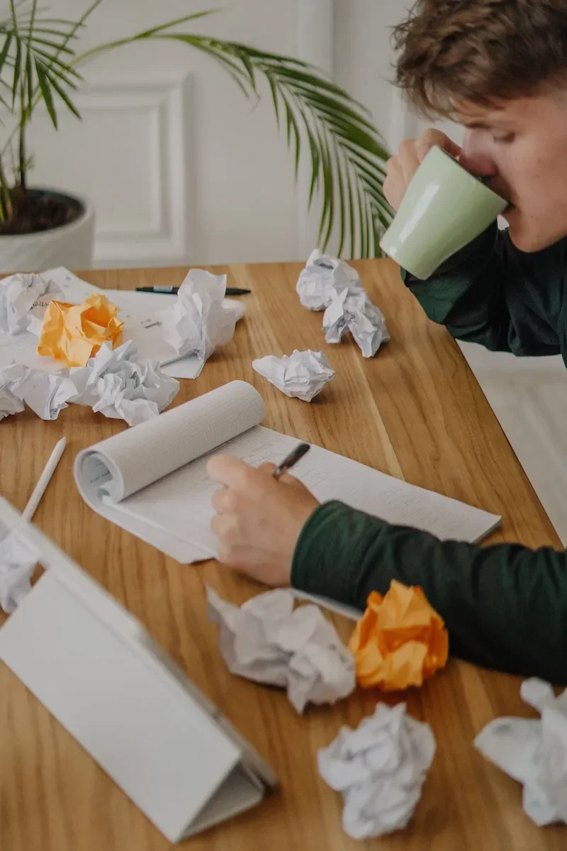 man at desk with scrunched up paper