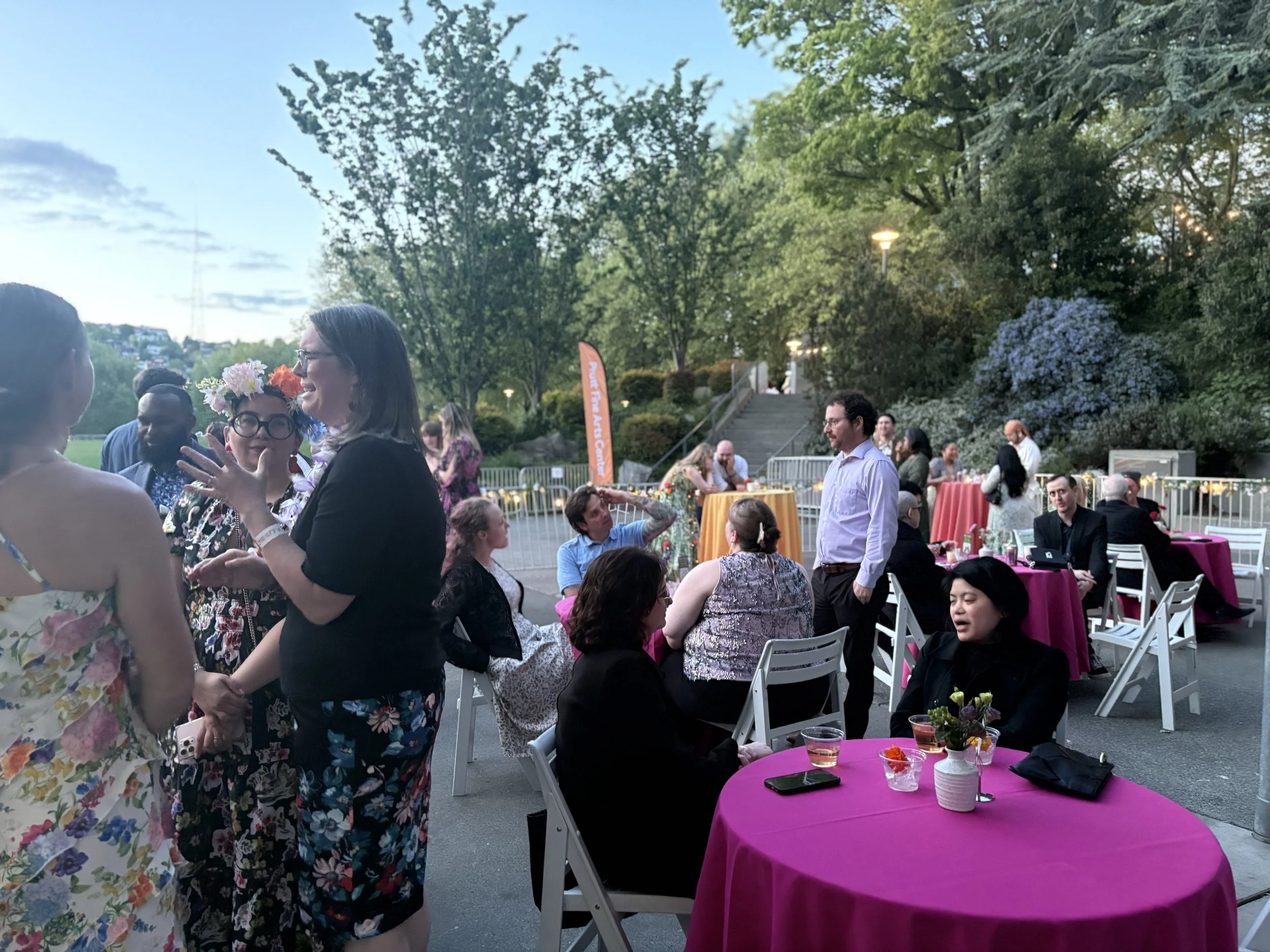 Event guests are chatting away at an outdoor event space, there is a mix of low tables and highboys  used in this space.