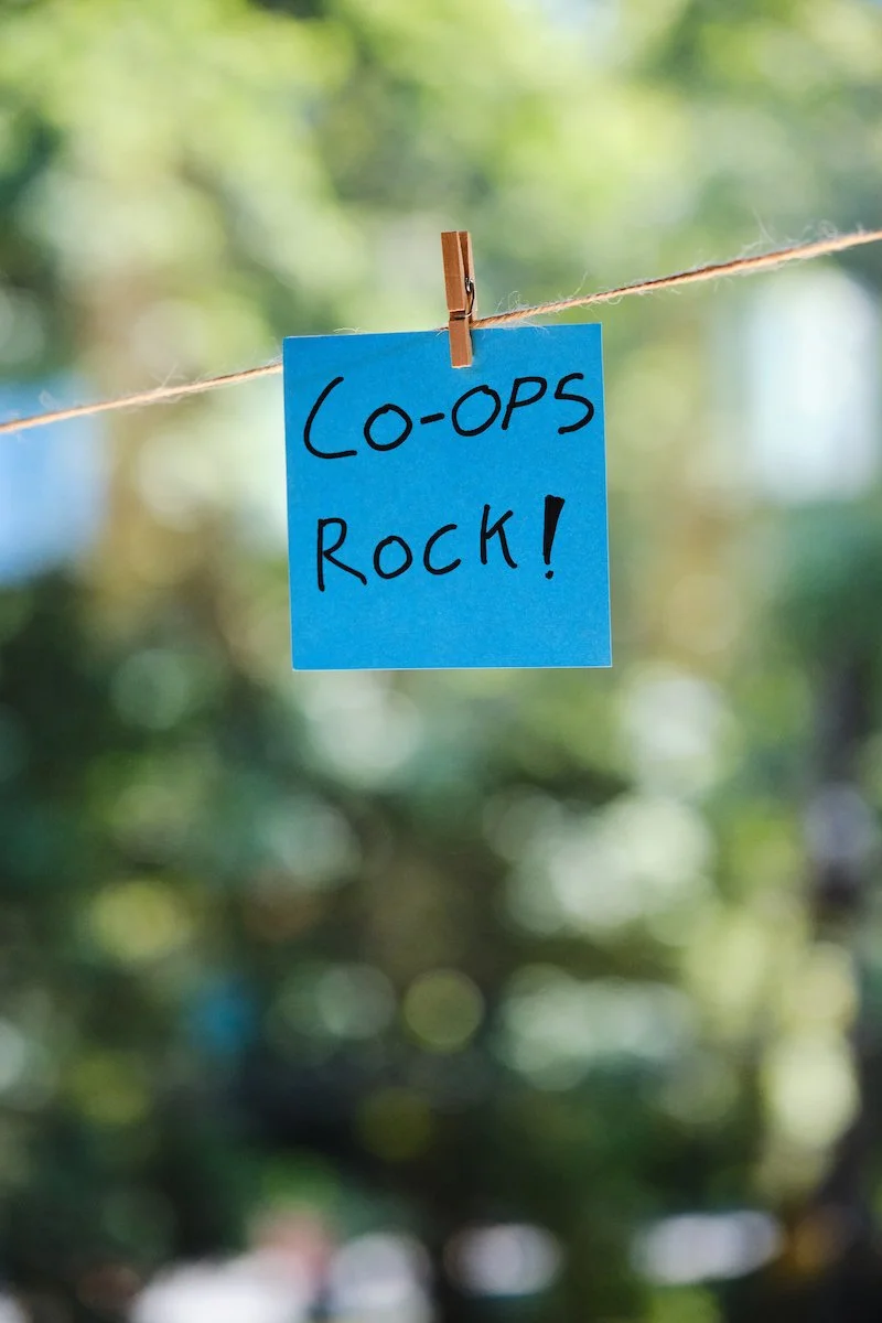 a blue post it note with "Coops Rock!" written on it clipped to twine in front of a window