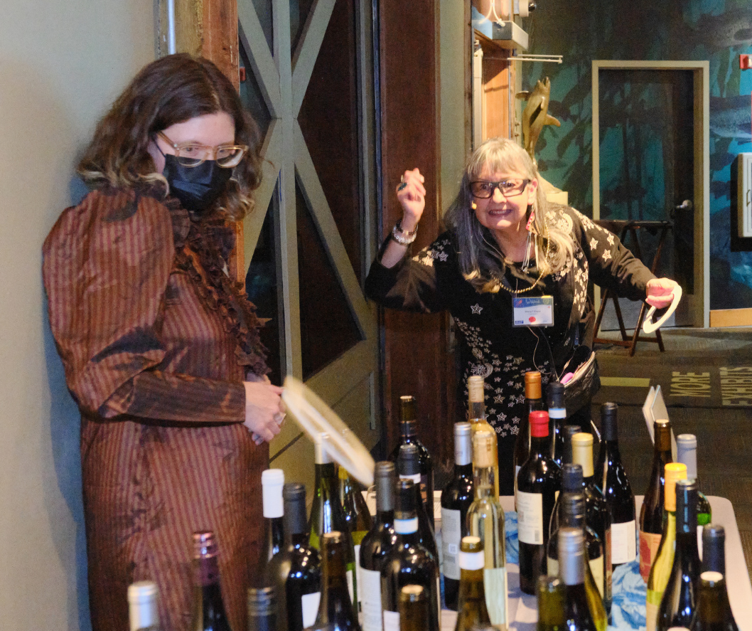 A smiling guest throws a ring at a table of wine bottles, eagerly aiming for a prize.
