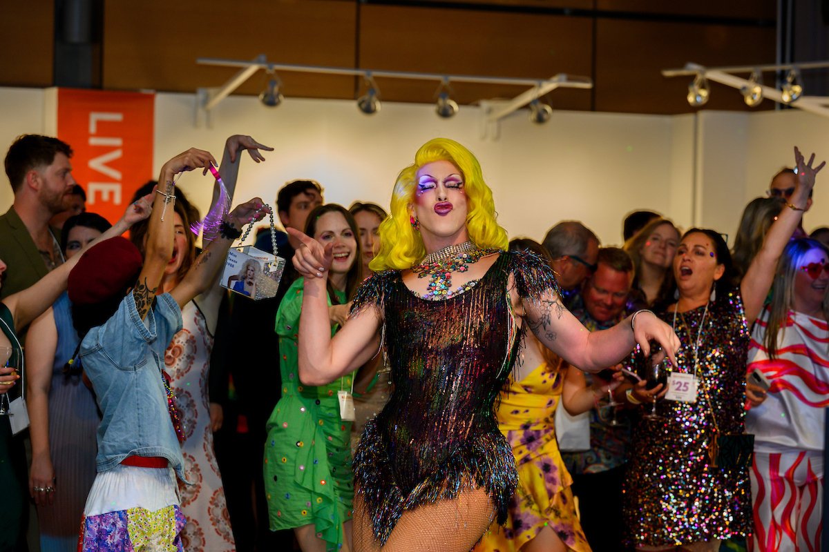 A drag queen performs in the middle and iss celebrated by a crowd