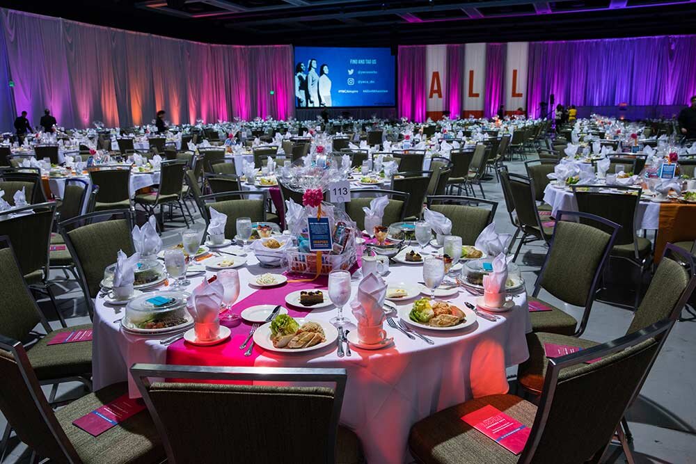 Large event venue with dining rounds, colorful lighting