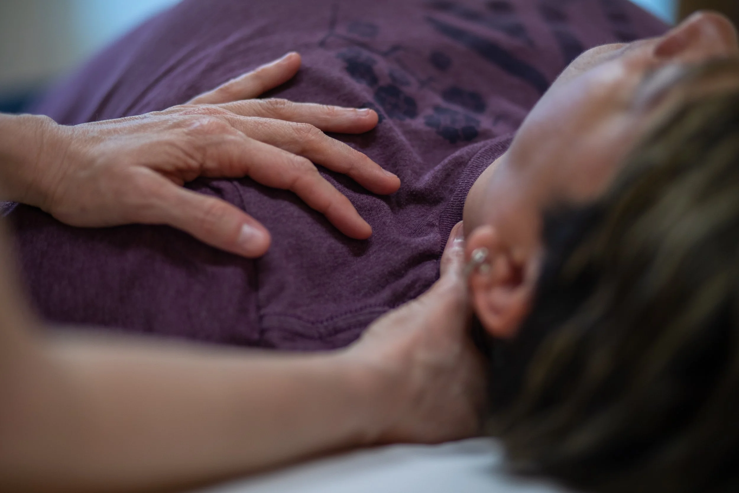Close-up of a therapist's hands resting on a client's chest and neck, holding sustained, gentle contact during a myofascial release therapy session at Halcyon Massage in  SODO, Seattle.