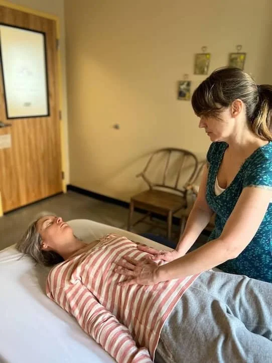 Jennifer Keller, LMT using gentle hand contact on a client’s abdomen to support visceral mobility and relieve core tension during a manual therapy session in SoDo, Seattle
