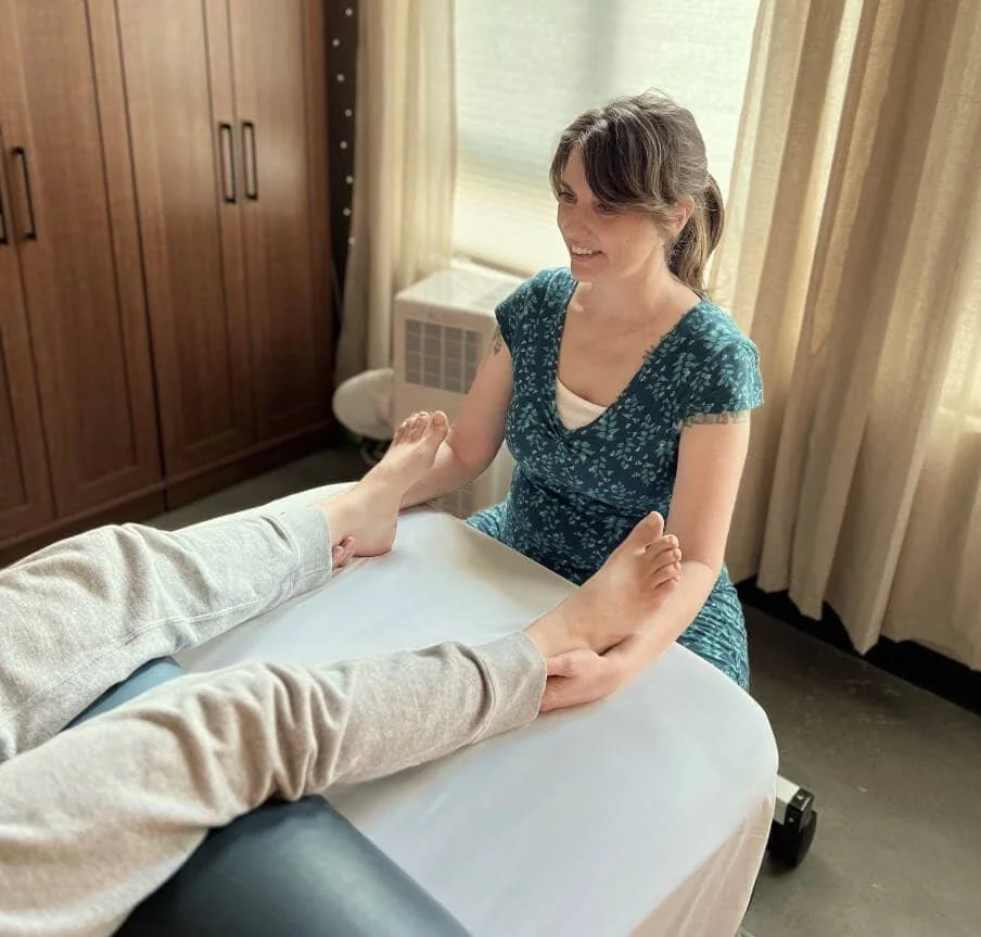 Jennifer Keller, CCST providing craniosacral therapy with light touch at the feet, supporting nervous system regulation in a quiet, restorative setting in SoDo, Seattle.
