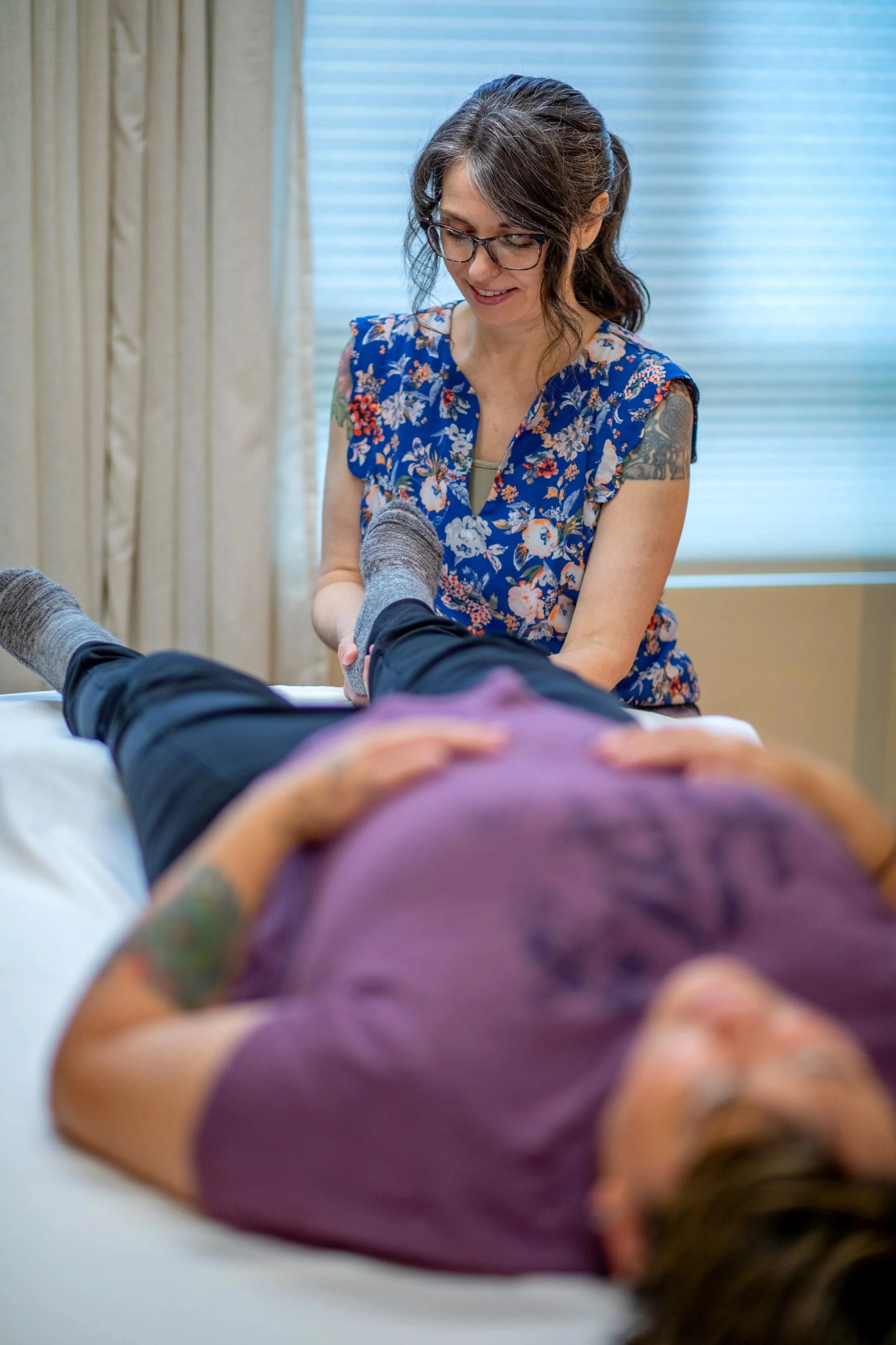 Hands-on myofascial release therapy on the calf and ankle area at Halcyon in Seattle SODO; the therapist's hands rest still, listening to the fascia.