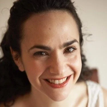 Close-up of a woman with dark hair smiling at the camera.