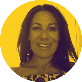 A woman with shoulder-length dark hair, smiling, wearing earrings and a patterned top, in front of a yellow background.