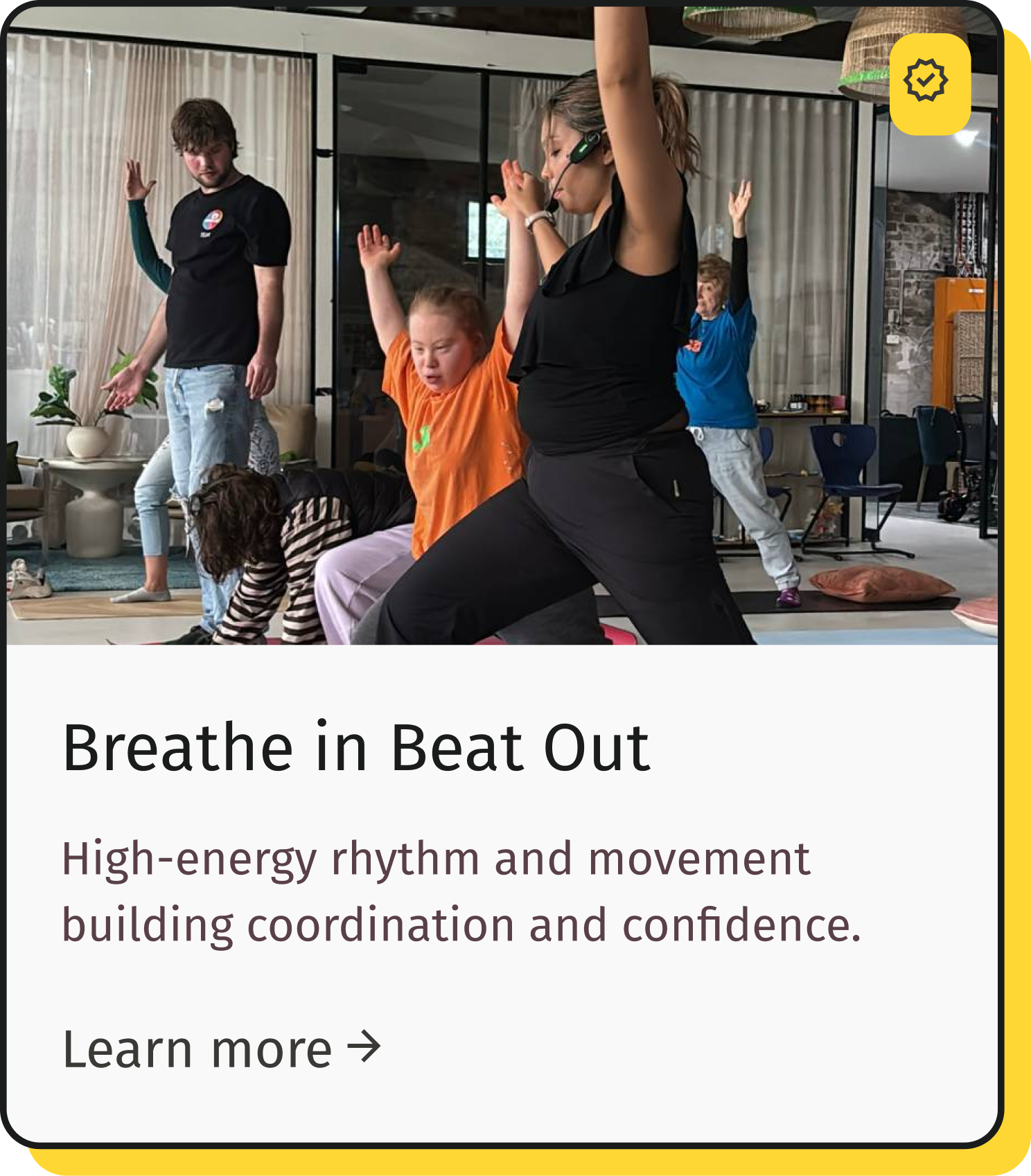 Group of children and an instructor in a yoga or dance class practicing stretching and movement indoors.
