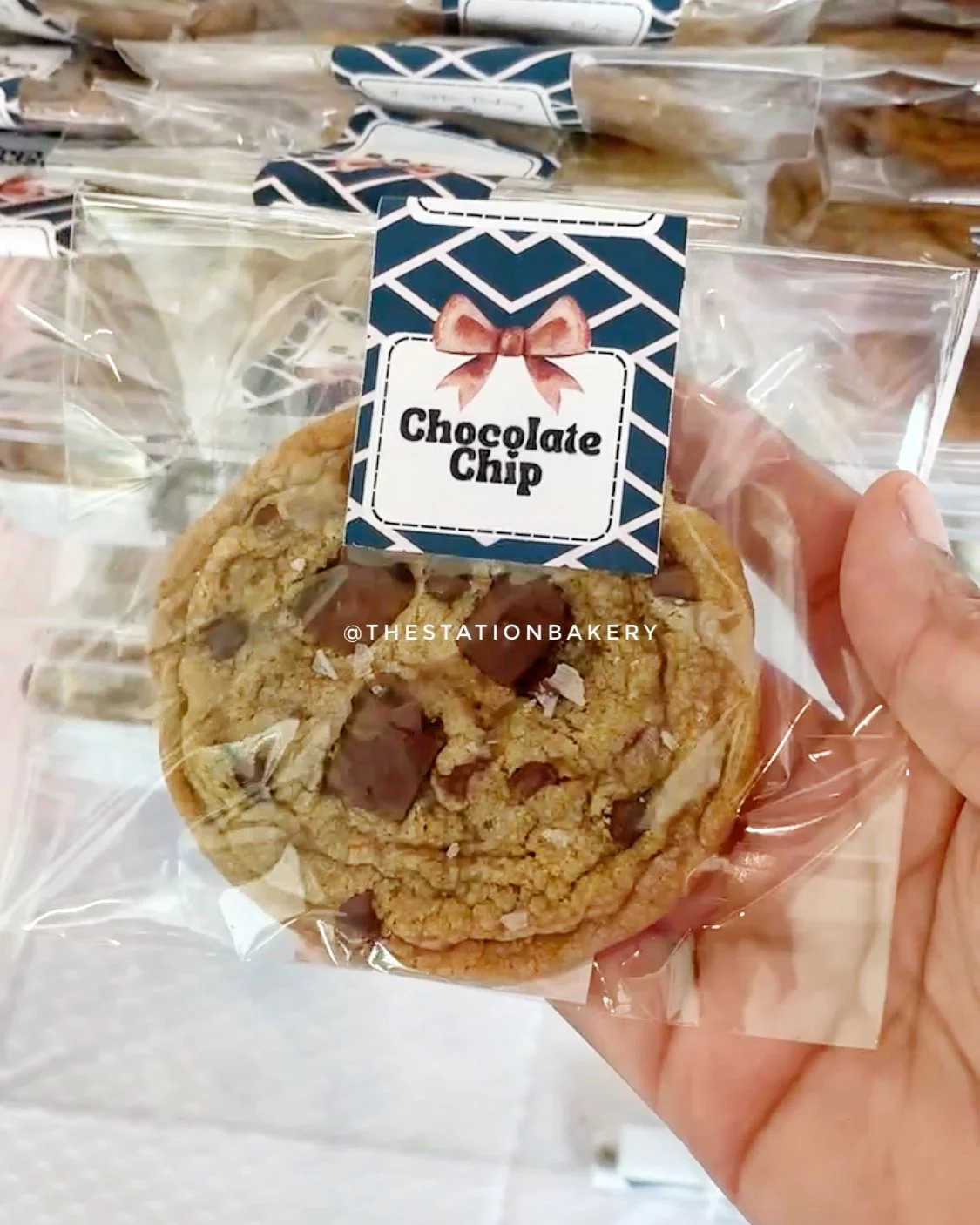 Chocolate chip cookie in a clear sealed bag with a bakery label sticker