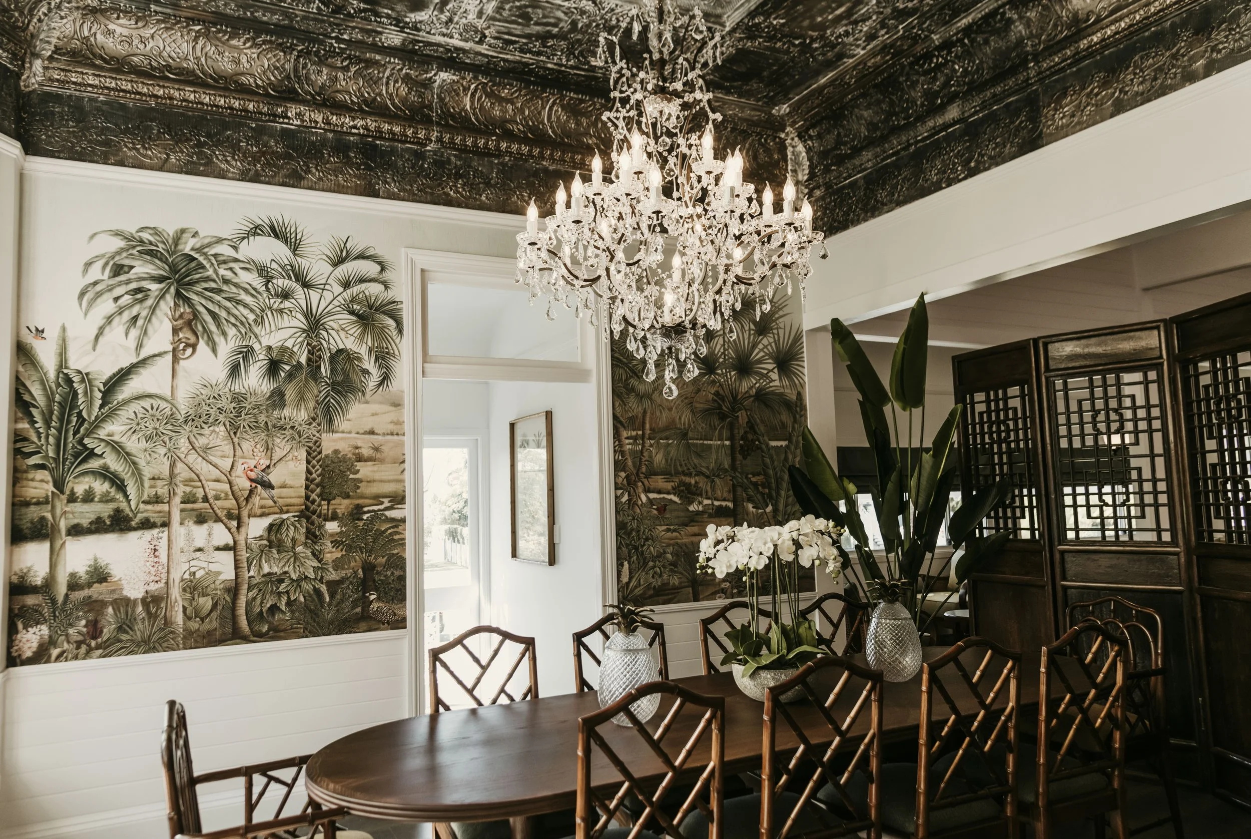 Private dining room with chandelier and palm wallpaper