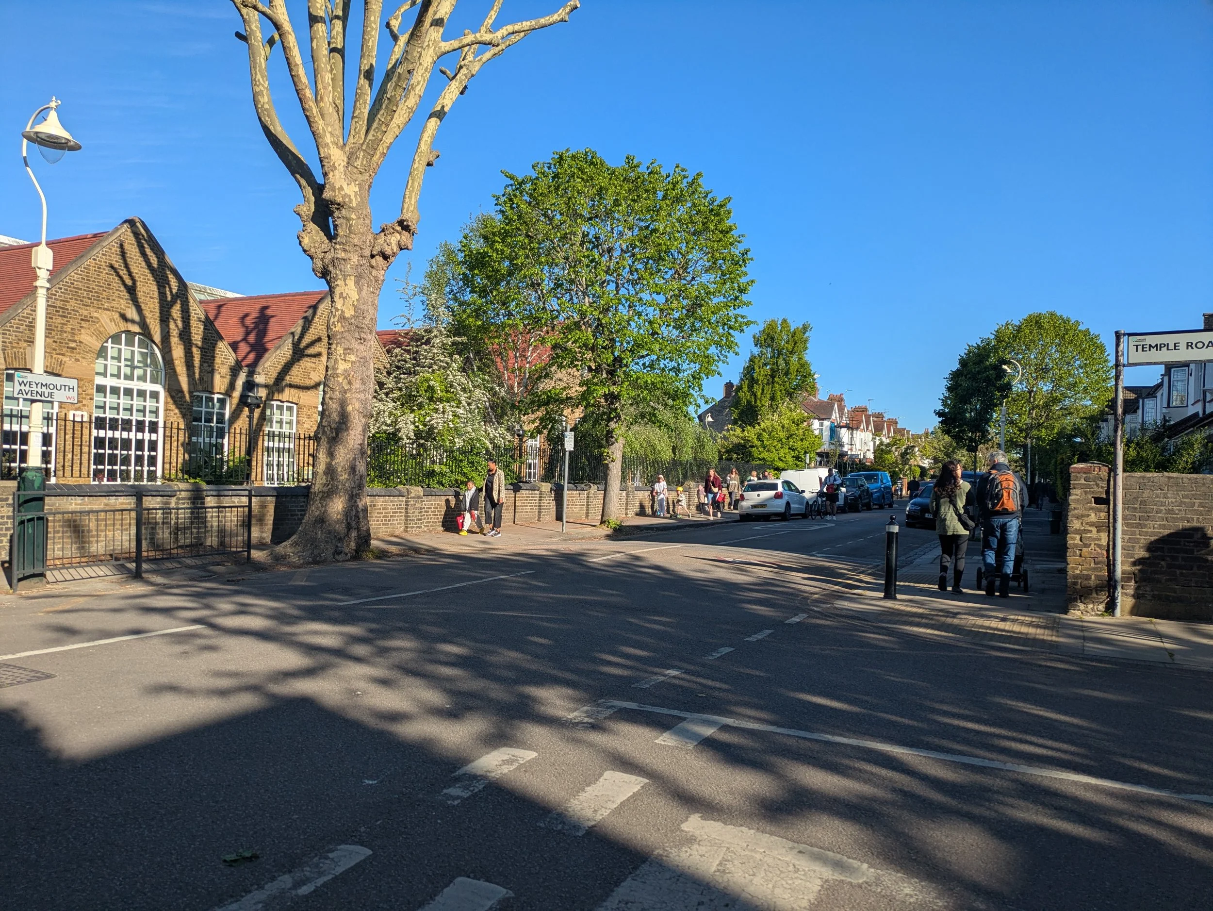 A road outside a school with no traffic and people walking to school.
