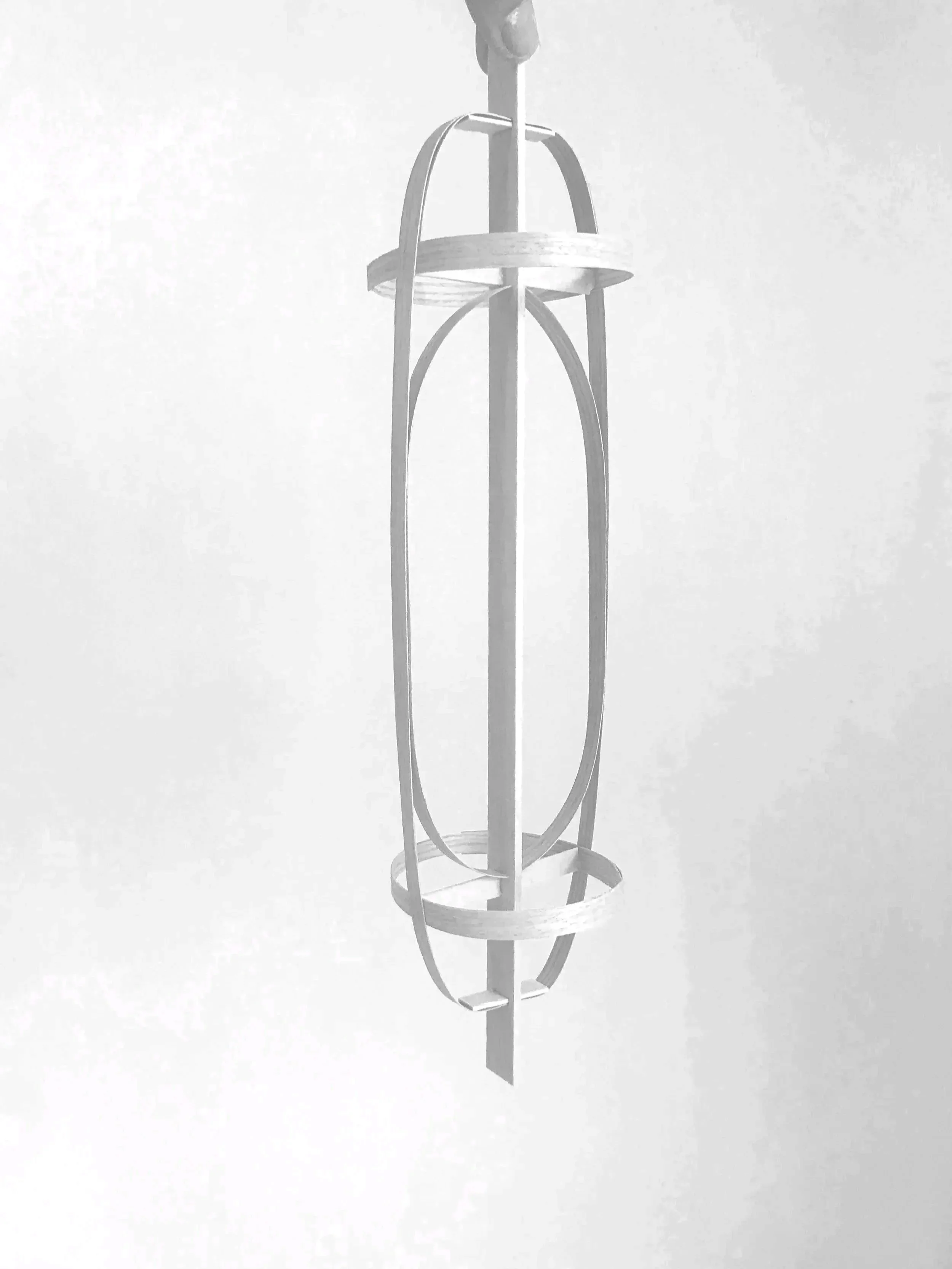 A modern, abstract hanging light fixture with a geometric design in a monochrome setting.