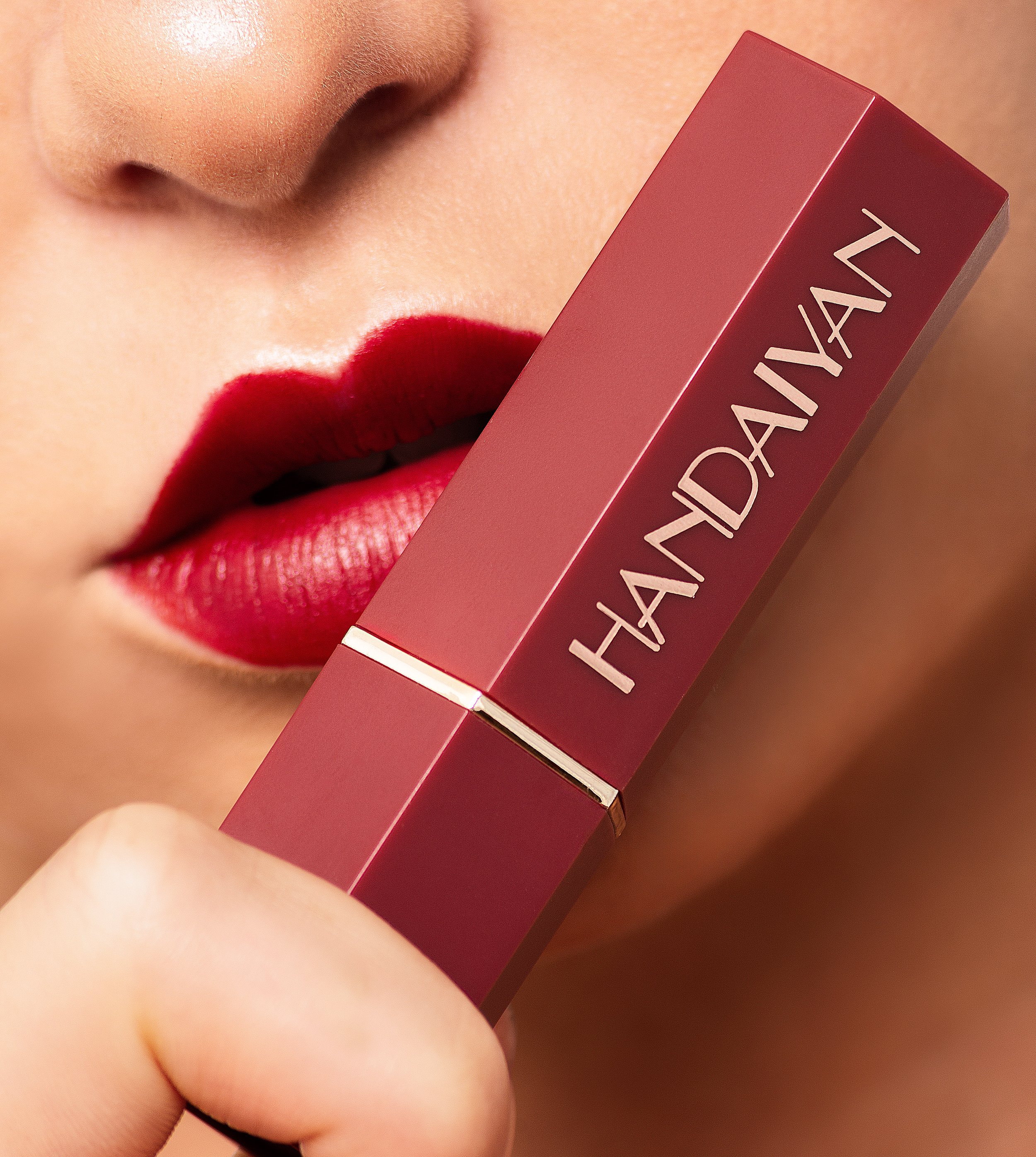 Close-up of a woman's lips with red lipstick and a person holding a red lipstick case labeled "Handaiyan."