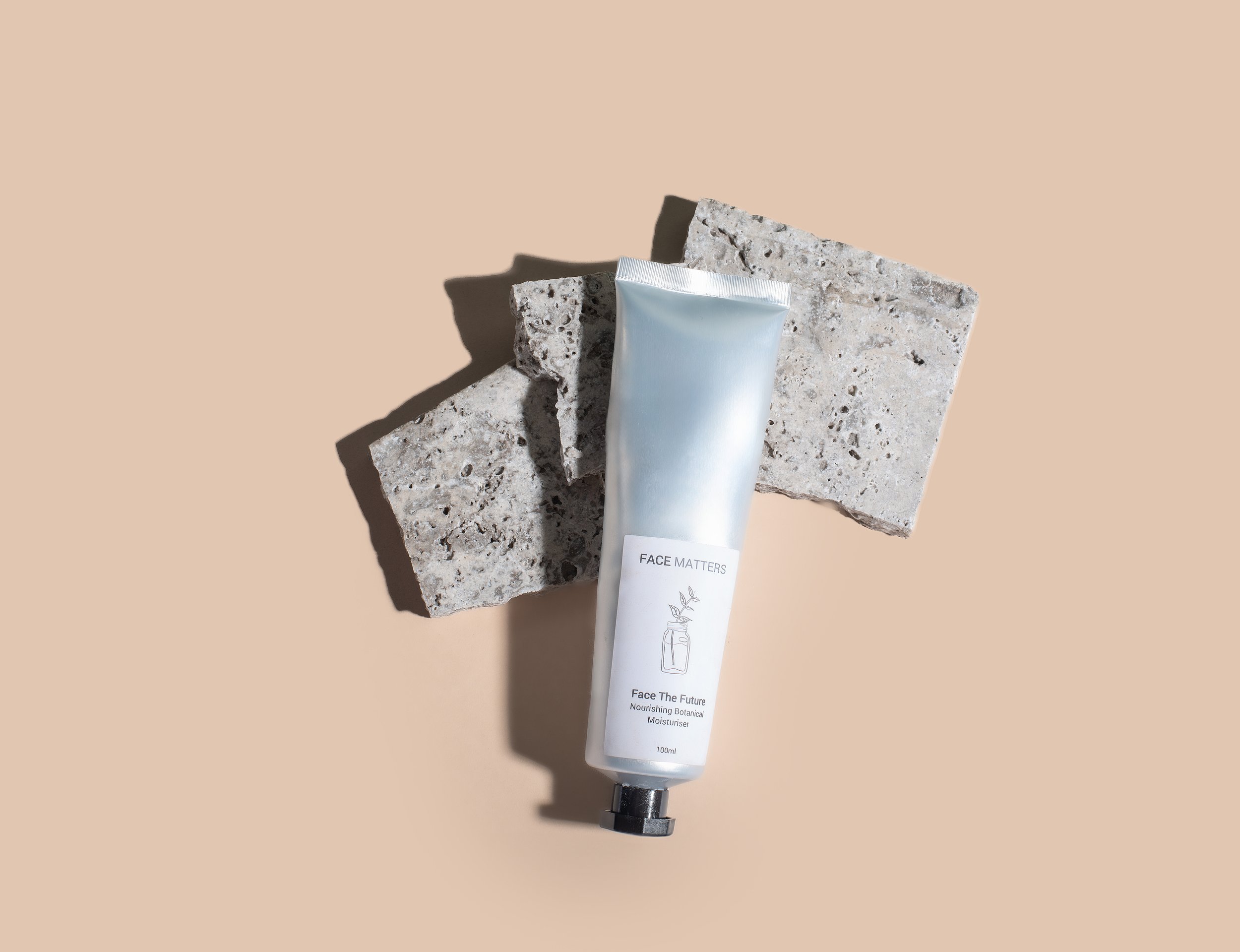Tube of botanical moisturizer labeled 'Face Matters' on textured stone background.