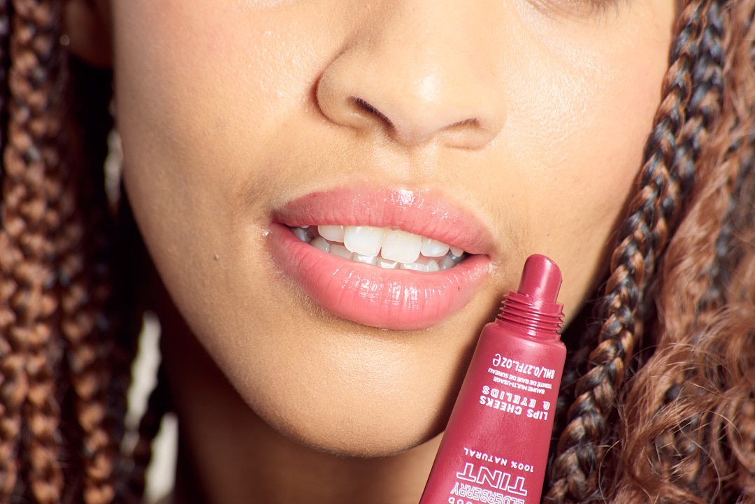 Close-up of a person with braided hair applying lip tint.