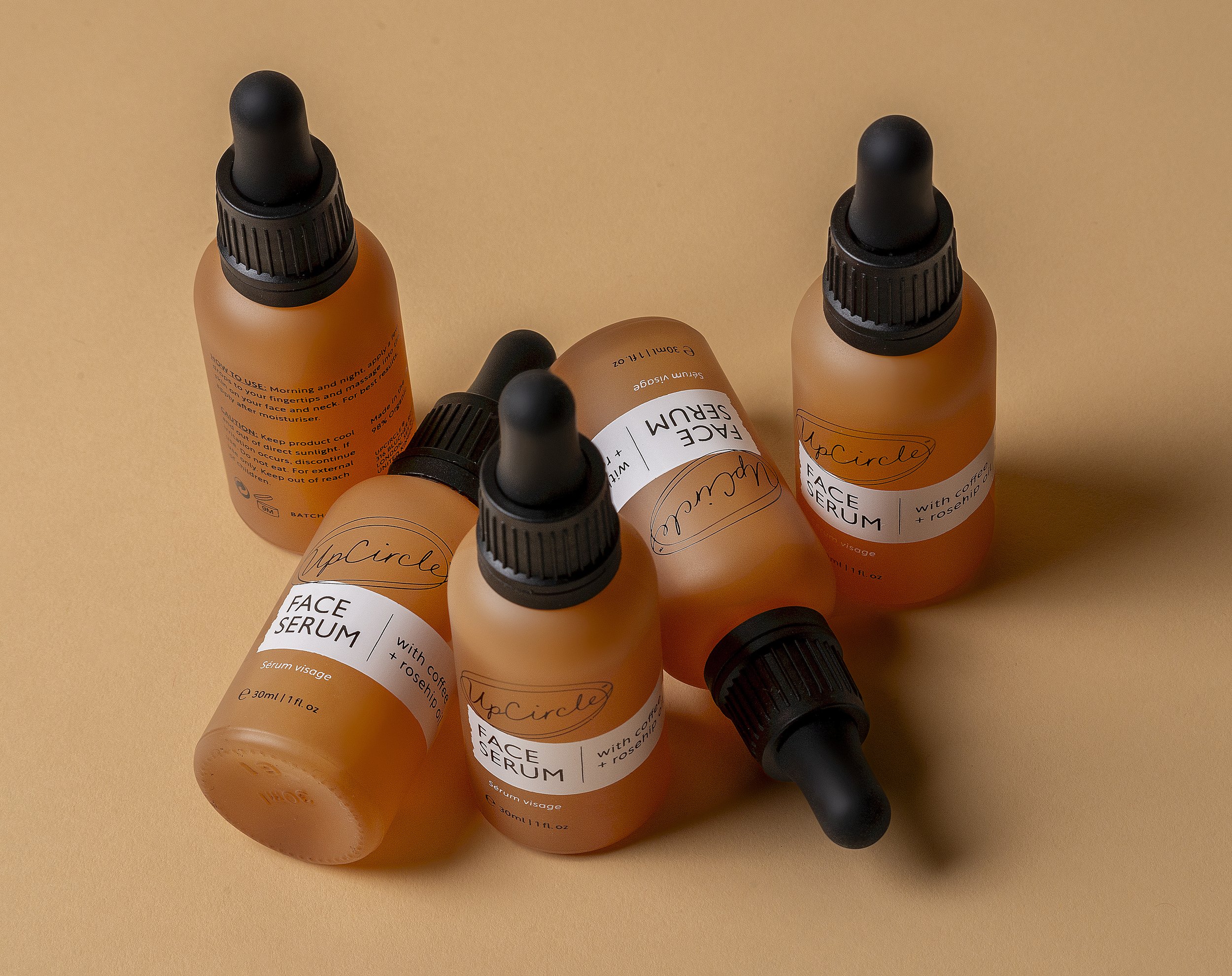 Bottles of face serum with dropper lids on a beige background.