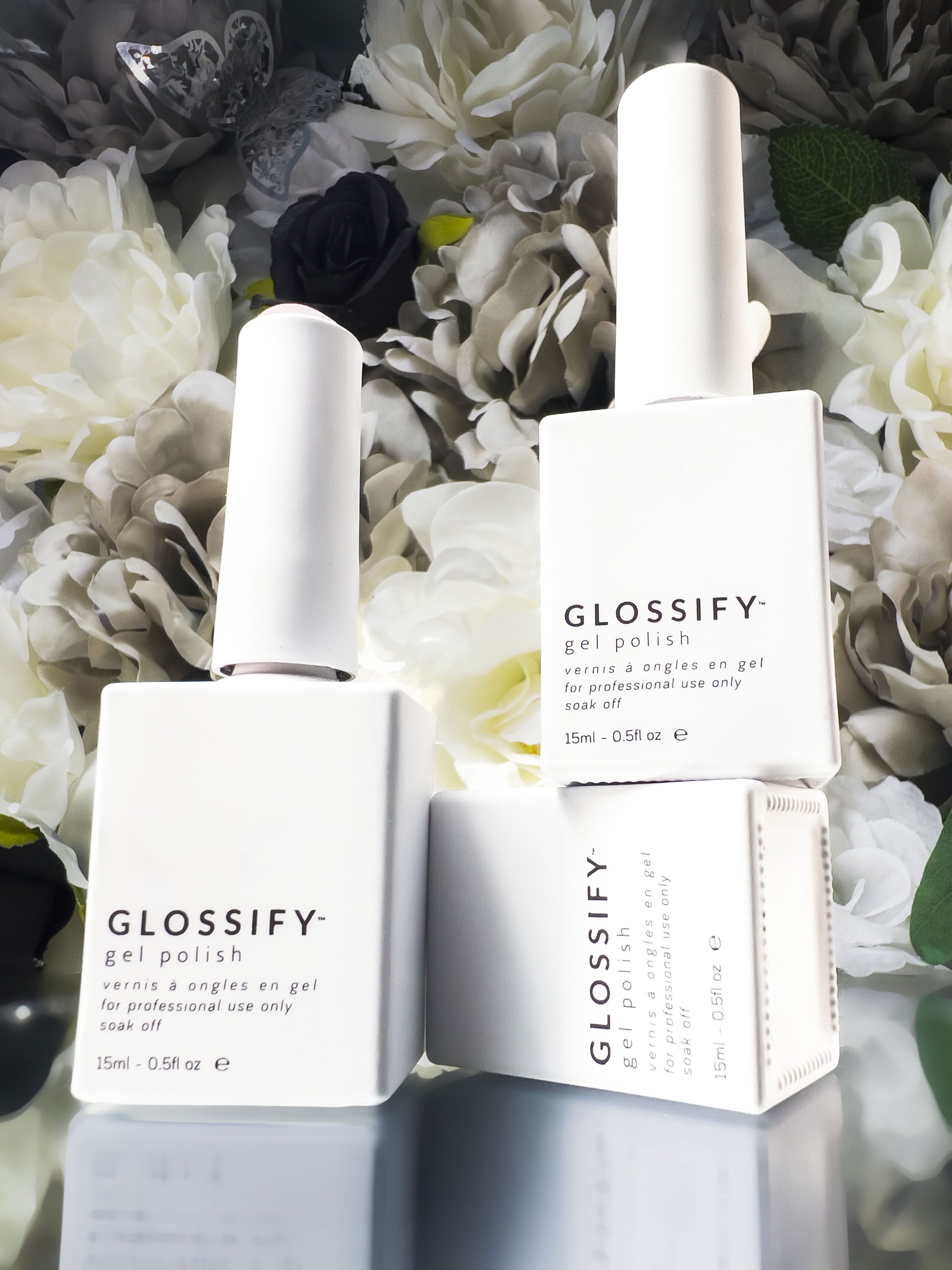Three bottles of GLOSSIFY gel polish against a floral background.