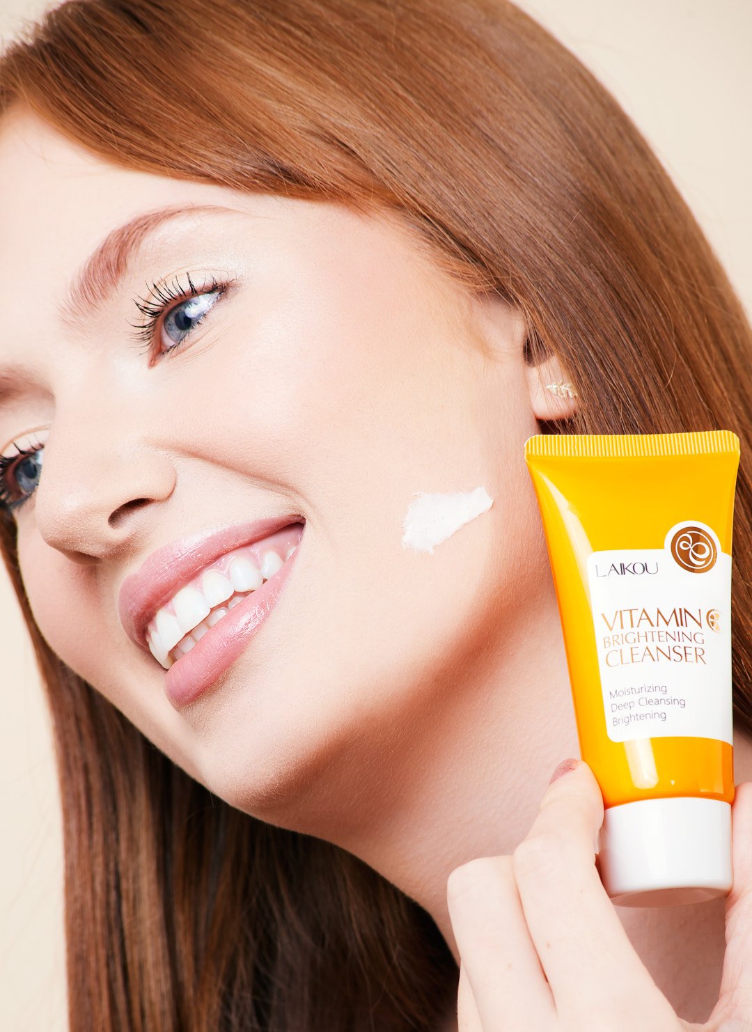 Smiling woman applying Laikou Vitamin C Brightening Cleanser to her cheek.